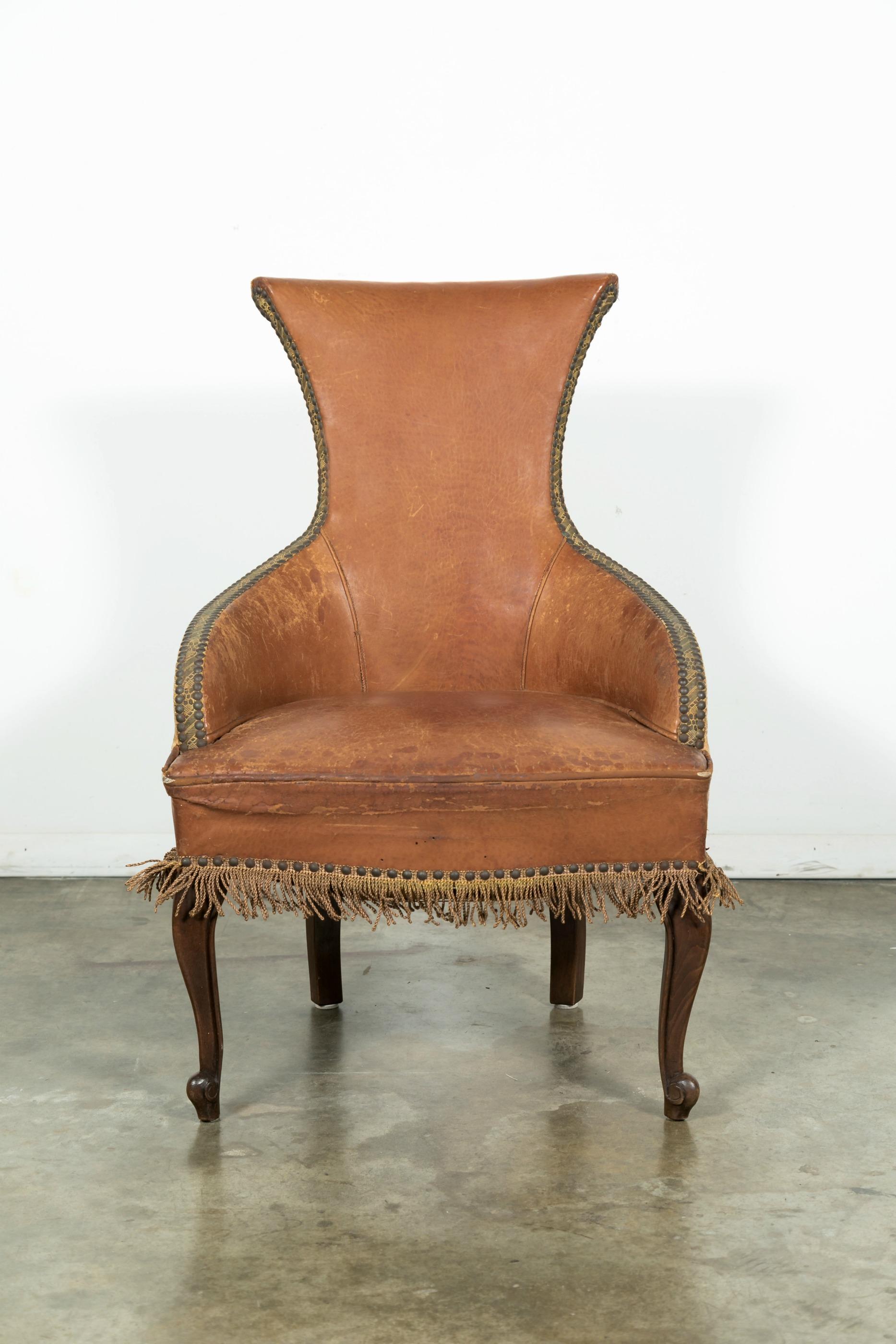 Antique French Louis XV style leather and velvet upholstered bergère having a high rolled back and finished with nail head trim and bullion fringe. Raised on short cabriole legs with scrolled French toes. Unique and beautiful with its graceful