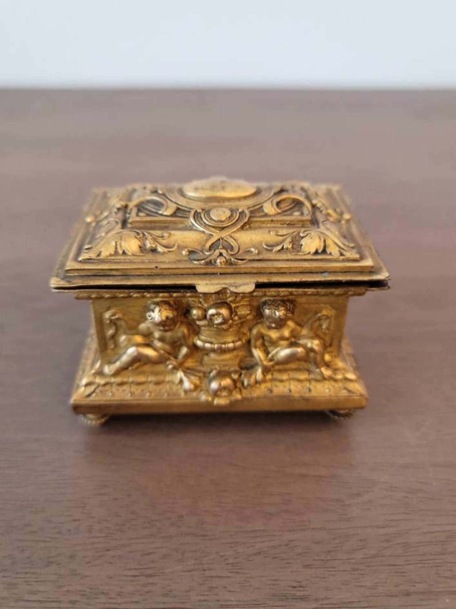 Eine feine, kleine französische Schmuckschatulle im neoklassizistischen Stil aus vergoldetem Metall. 

Das um die Wende vom 18. zum 19. Jahrhundert entstandene, außergewöhnlich gut ausgeführte, zierliche Meisterwerk hat die Form einer rechteckigen