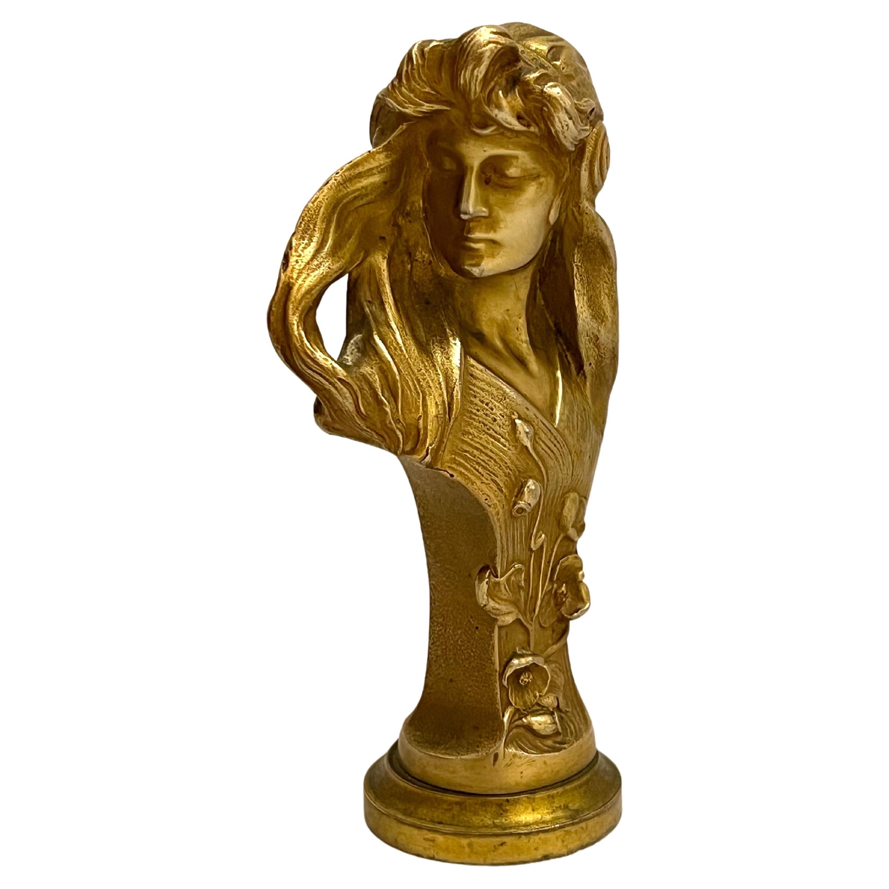 A beautifully detailed gilt bronze bust of a young woman by Austrian artist Hans Muller. This work is signed on the back, H Muller. The long flowing hair of the model creates a sense of movement around her delicate face and decollete. There are