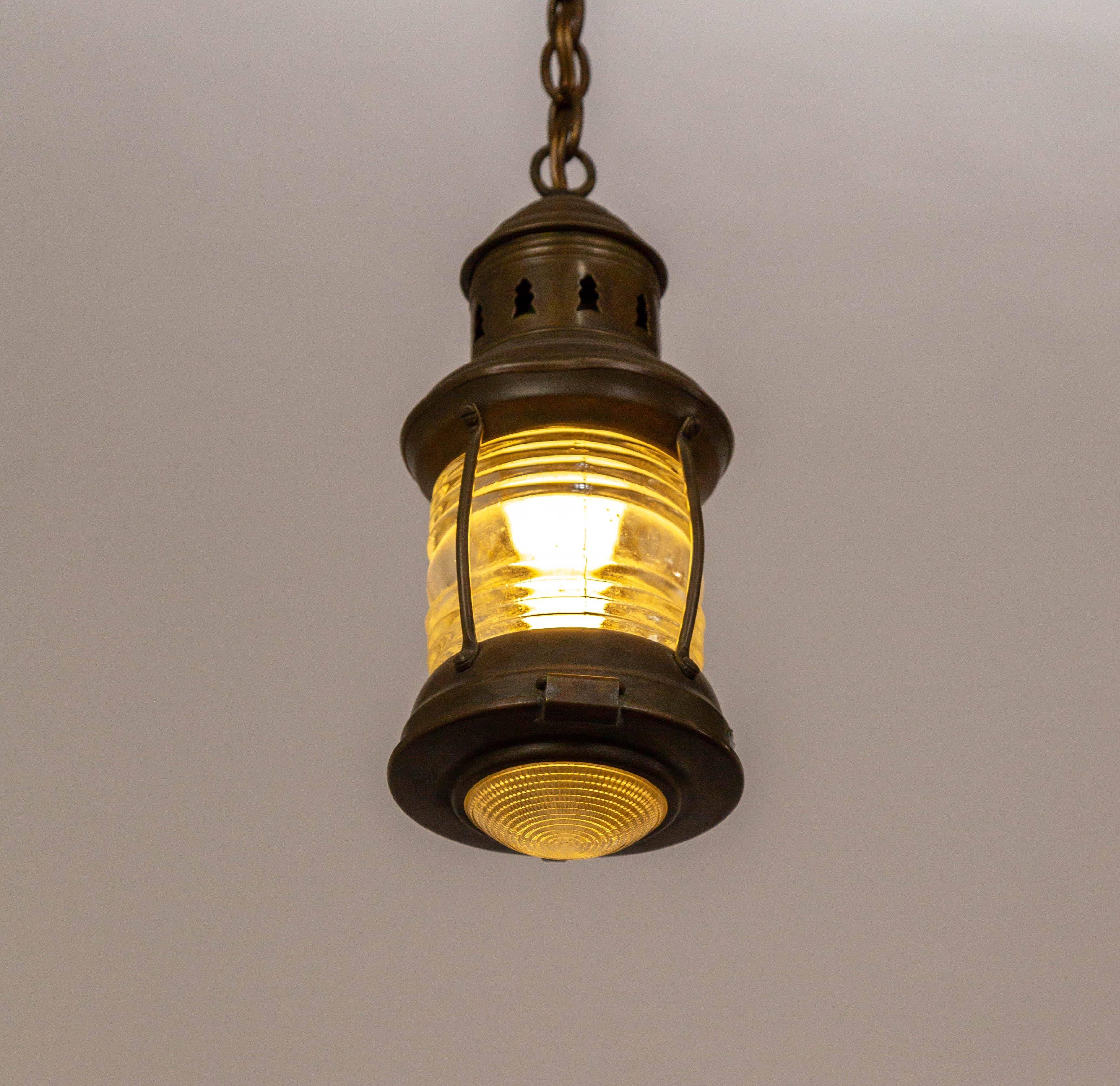An early 20th-century hanging lantern in cylindrical form with beautiful diffusion from the Fresnel glass and textured bottom diffuser. With a bronze-toned patina and a long chain. Newly wired. 4.5