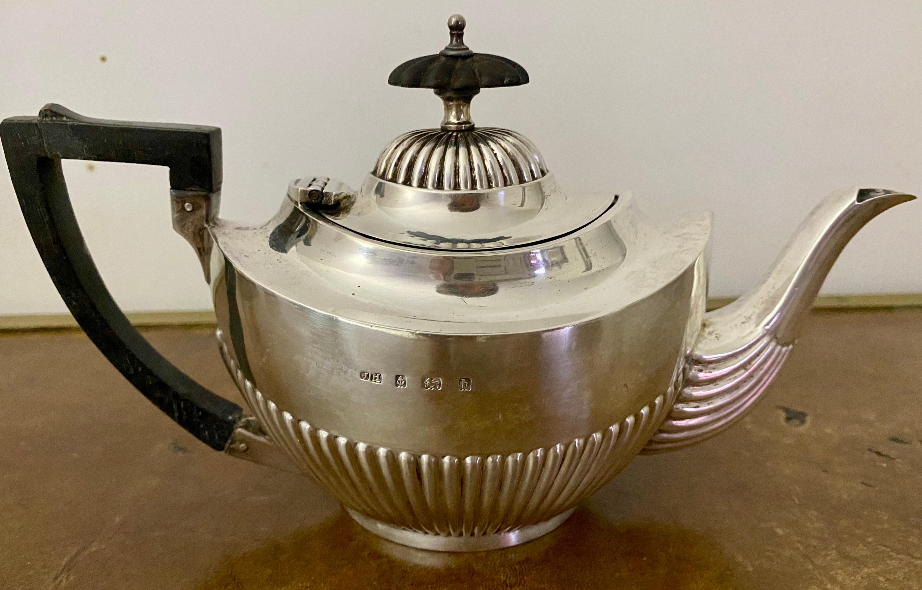Esta encantadora tetera pequeña de soltero es una pieza de plata antigua maravillosamente única, destinada al uso de una sola persona. La pieza tiene forma ovalada, la parte inferior del cuerpo está adornada con decoración estriada. Los sellos están