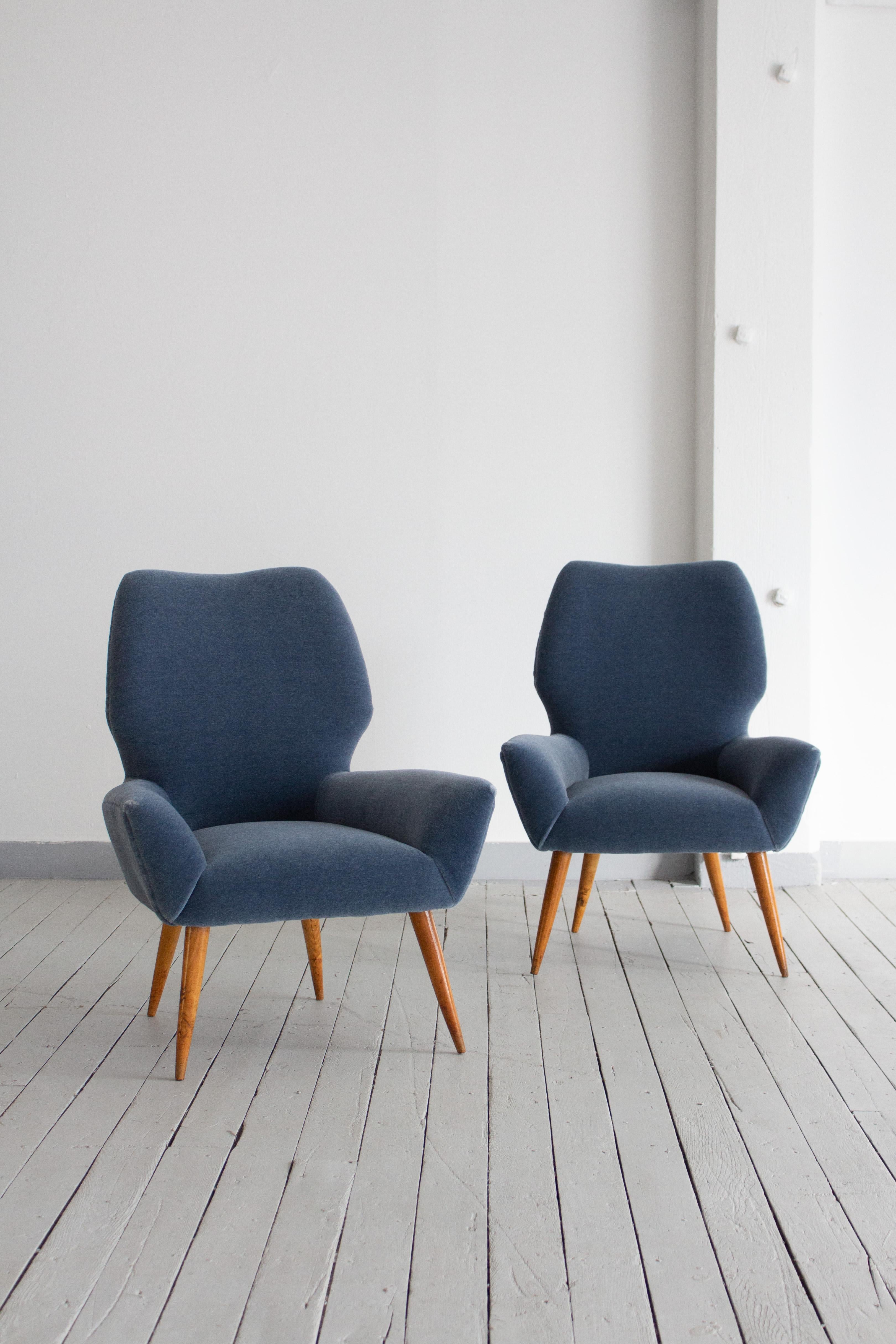 A pair of mid century Italian armchairs in the style of Melchiorre Bega. Petite in size. Newly upholstered in a dusty blue mohair. Patinaed wood legs. Sourced in Northern Italy.