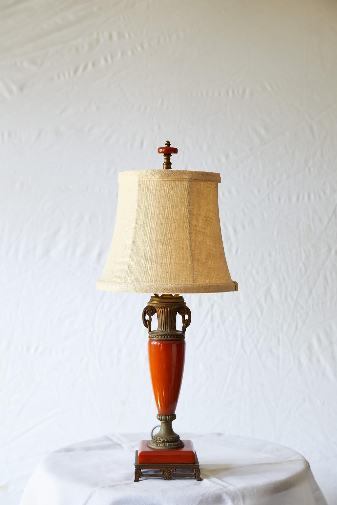 Early 20th century petite table lamp of the Art Deco period made of red orange Bakelite and in a slender urn-shaped neoclassical form.