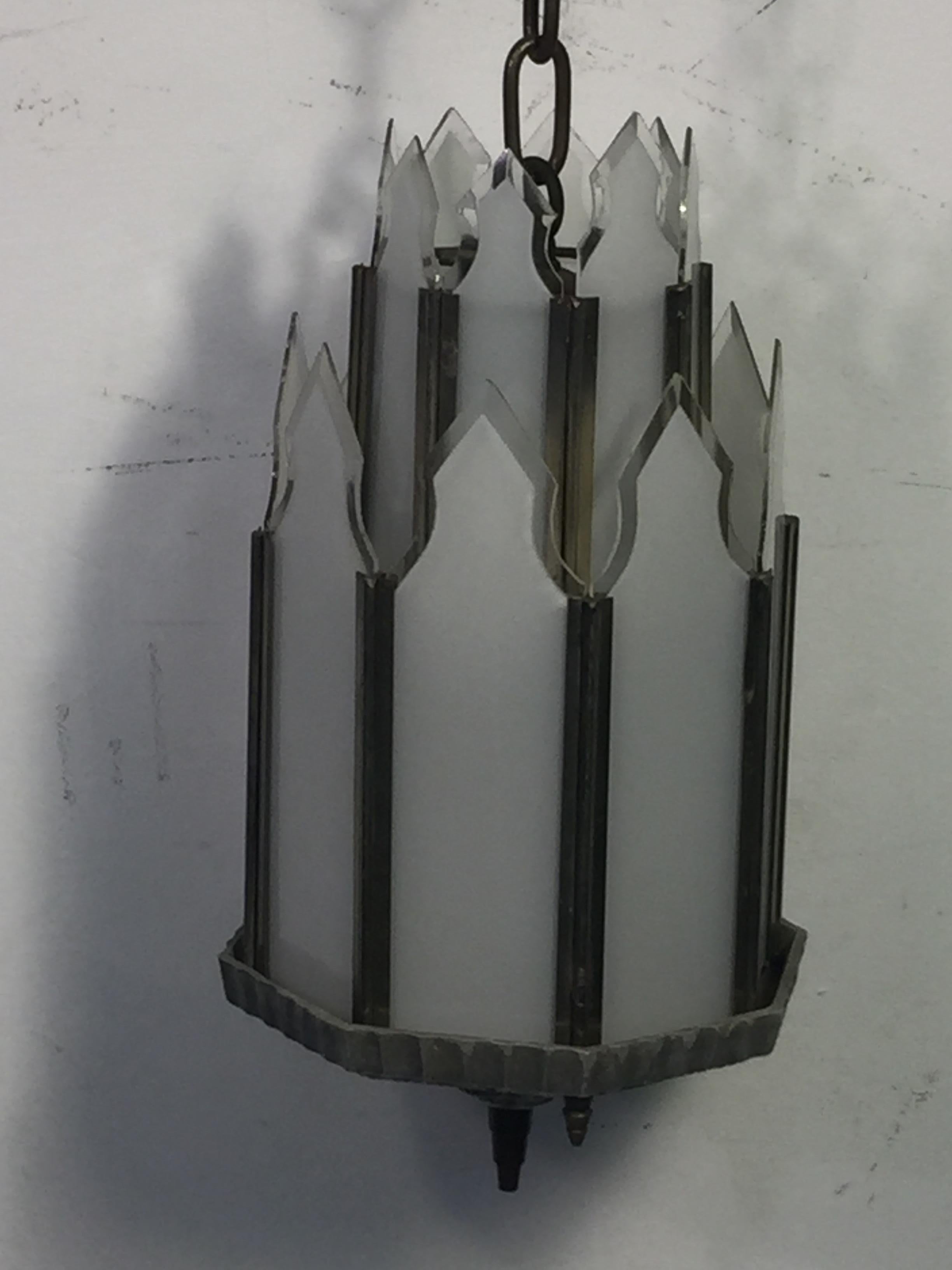 Art Deco skyscraper design chandelier with a matte chrome frame and ceiling cap with milk glass edged with clear glass panels. There is a milk glass panel at the bottom to allow the light to shine through. Double tier form with one light fixture.