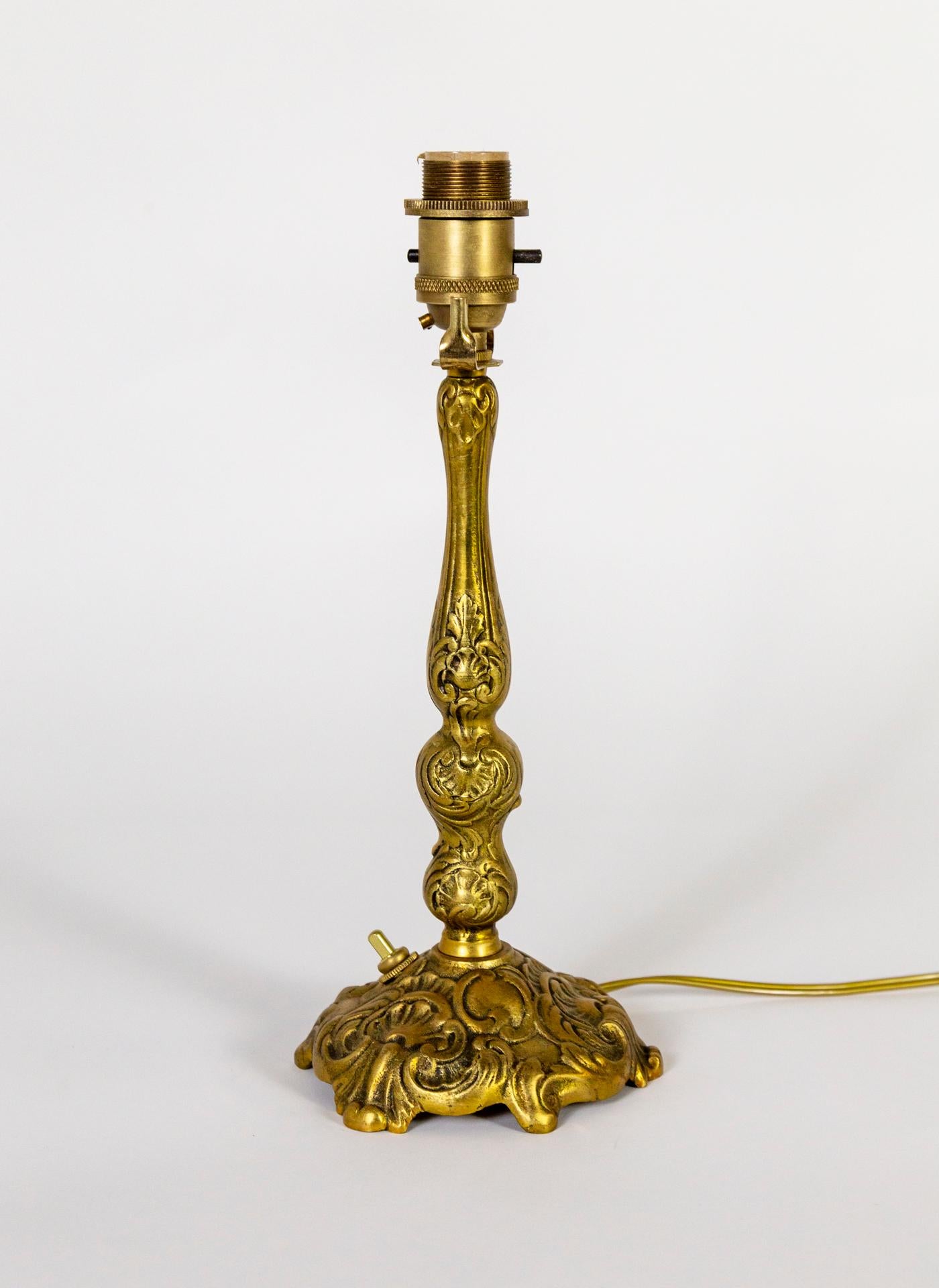 A petite, brass table lamp, finely cast with an ornate pattern of C-curves and acanthus leaves. It has a switch on both the base and socket and is newly wired. It has a saddle and a screw top socket to accommodate various shades. 5.75