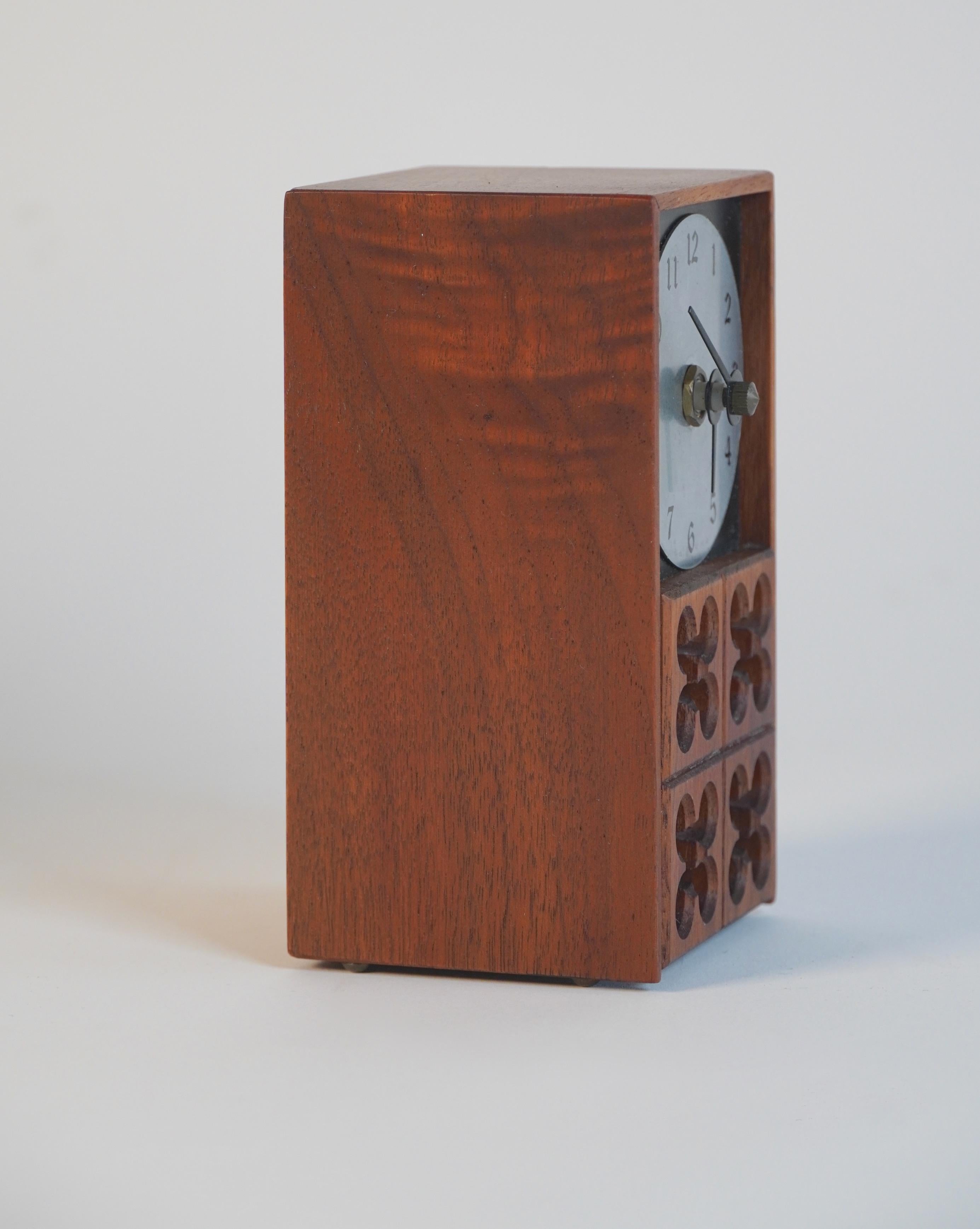 Petite desk clock by industrial designer Arthur Umanoff for the Howard Miller clock company. Crafted of walnut and aluminum with his trademark five circle pattern motif on the front of the clock. With a sliding back to access the movement for