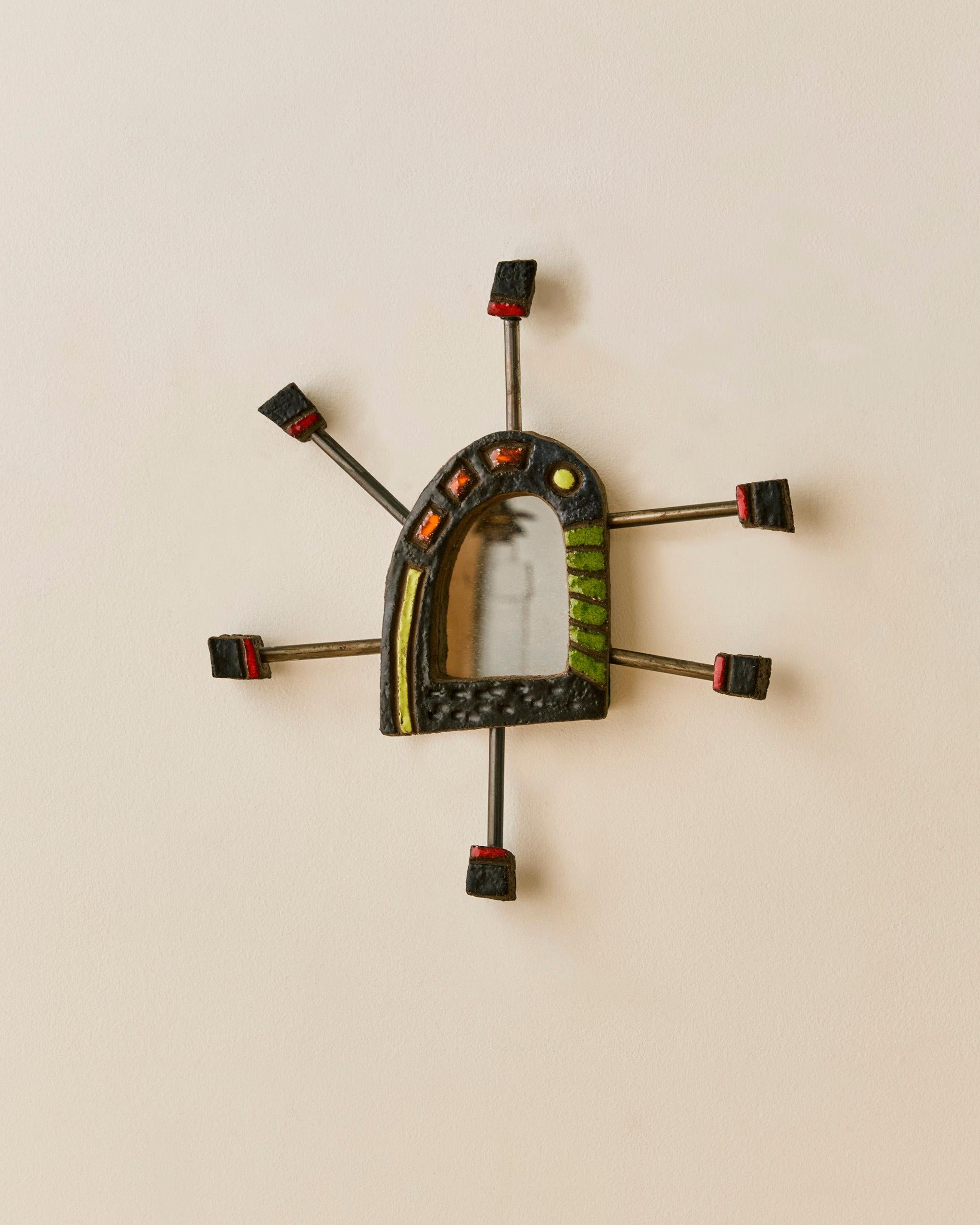 Petit miroir folklorique artisanal présentant un motif de pointes multicolores. Signé et numéroté au dos. 