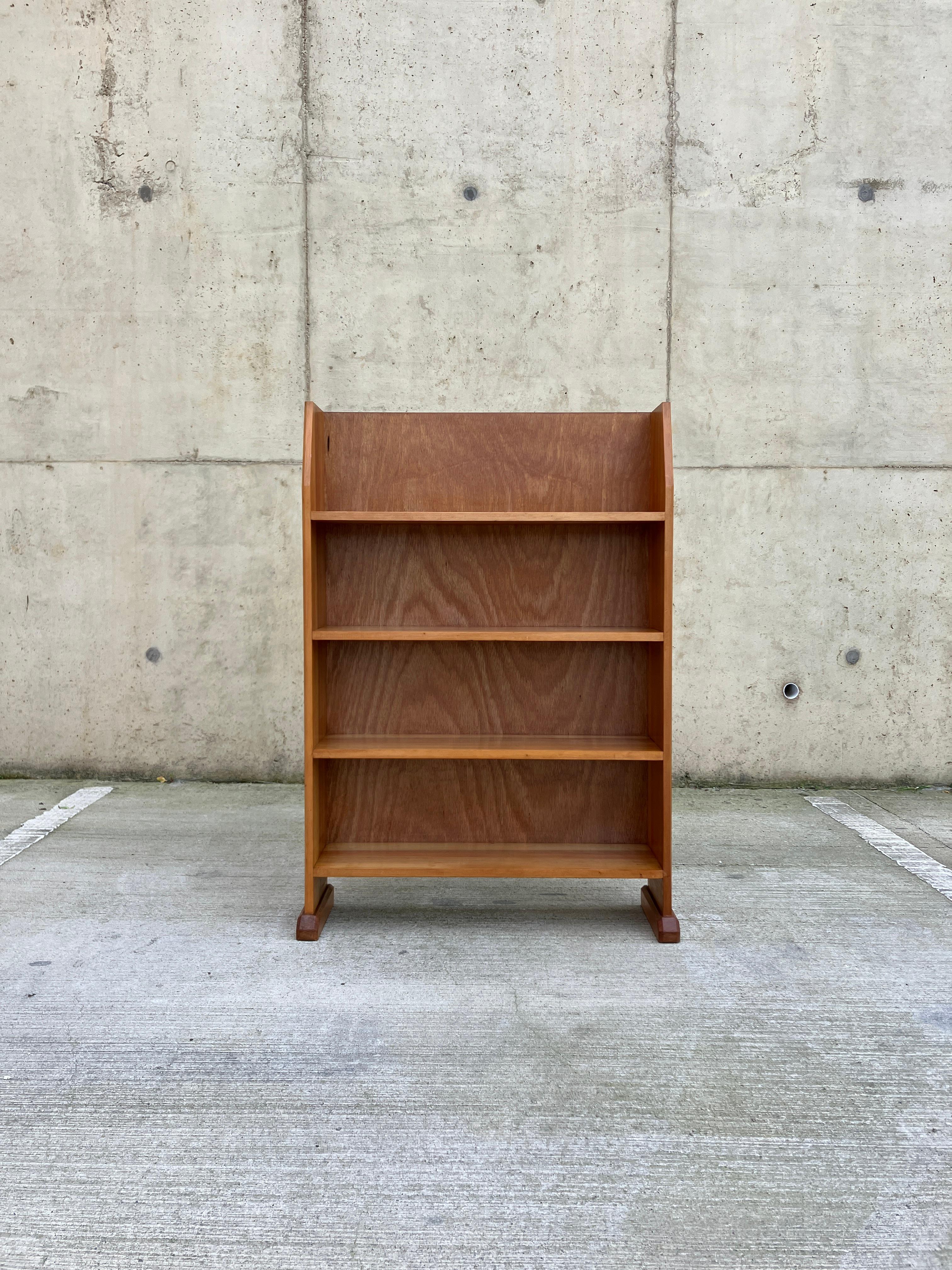A small vintage wooden bookcase. The bookcase is from the midcentury era with heavy Arts and Crafts influence. Stunning colour and patina to the beautifully grained two-tone Beechwood. The bookcase has beautiful Arts and Crafts details, such as the