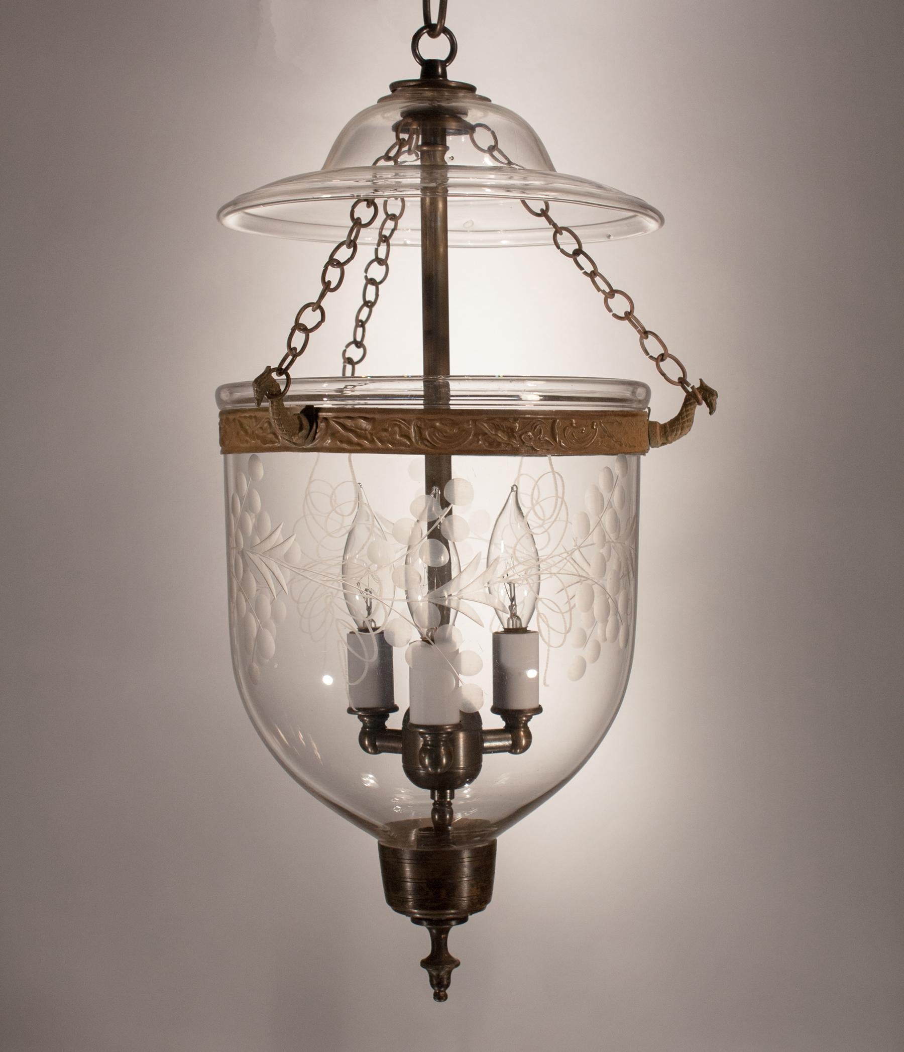 A lovely hand blown glass bell jar lantern with an etched vine motif. This petite antique pendant light is accented with its original brass band and finial candleholder base. The period smoke lid with a classic bell form further enhances the bell