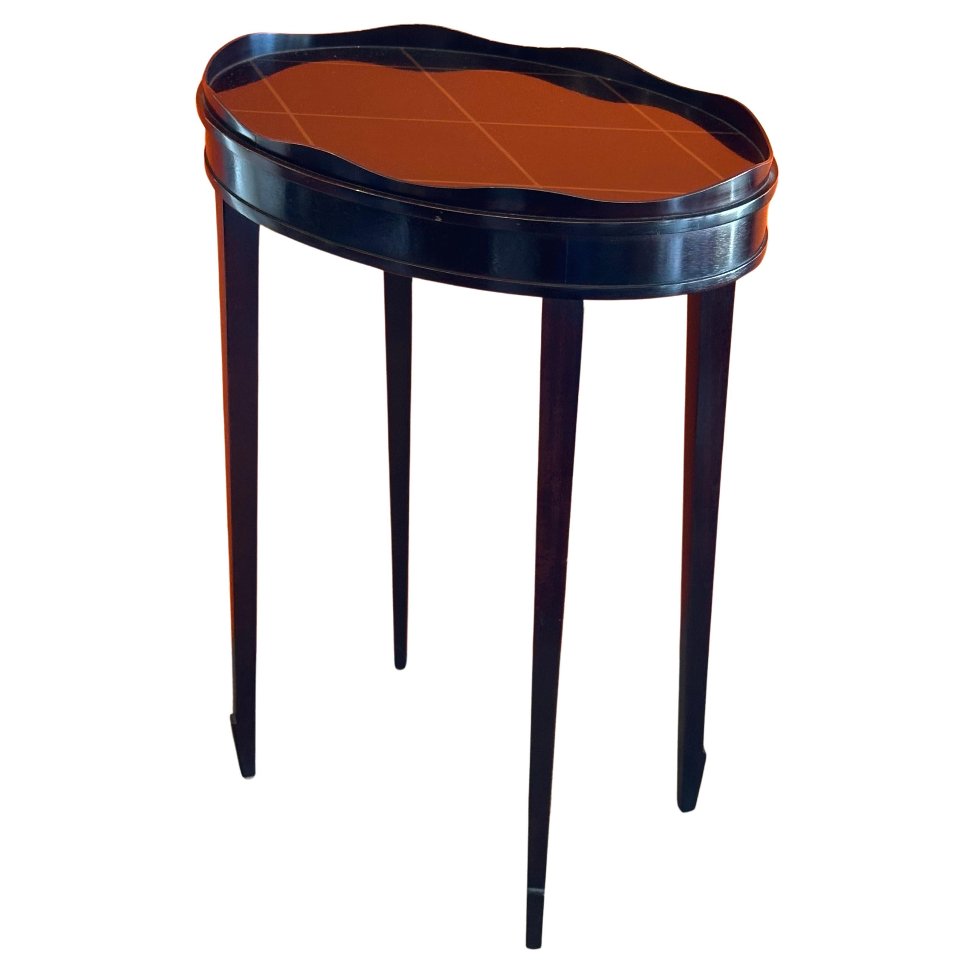 Petite black lacquered oval gallery edge side table by Barbara Barry for Baker circa 2000s. The table has a muted gold lattice painted top with four gently splayed arrow tip legs. This is a very stylish and functional piece that is in very good