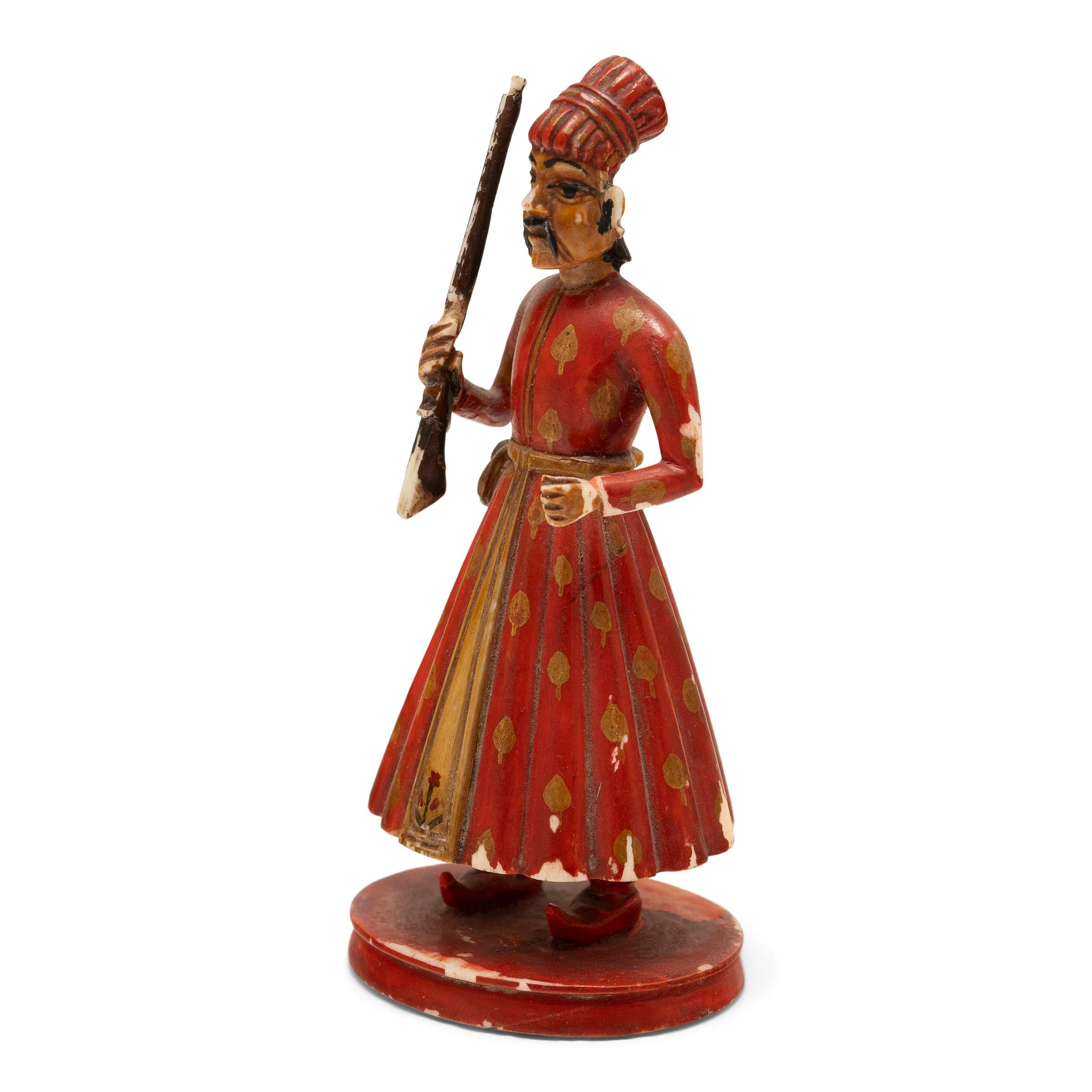 This early 20th century figurine is hand-carved of bone to depict an Indian soldier holding a musket rifle. Modeled after Sowar cavalrymen who served under the British East India Company, the petite figure is dressed in long robes painted with deep