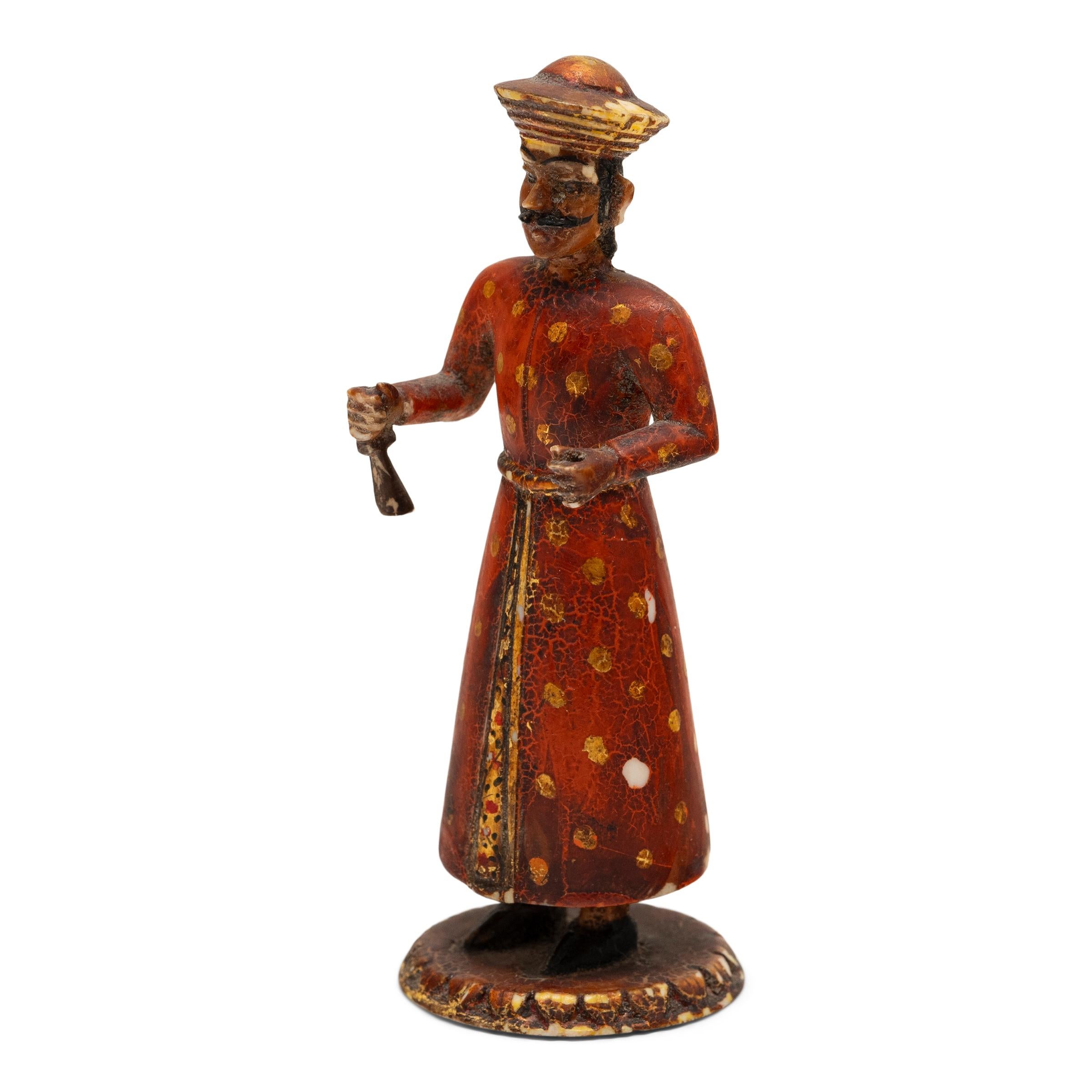 This early 20th century figurine is hand-carved of bone to depict an Indian soldier holding a musket rifle. Modeled after Sowar cavalrymen who served under the British East India Company, the petite figure is dressed in long robes painted with deep