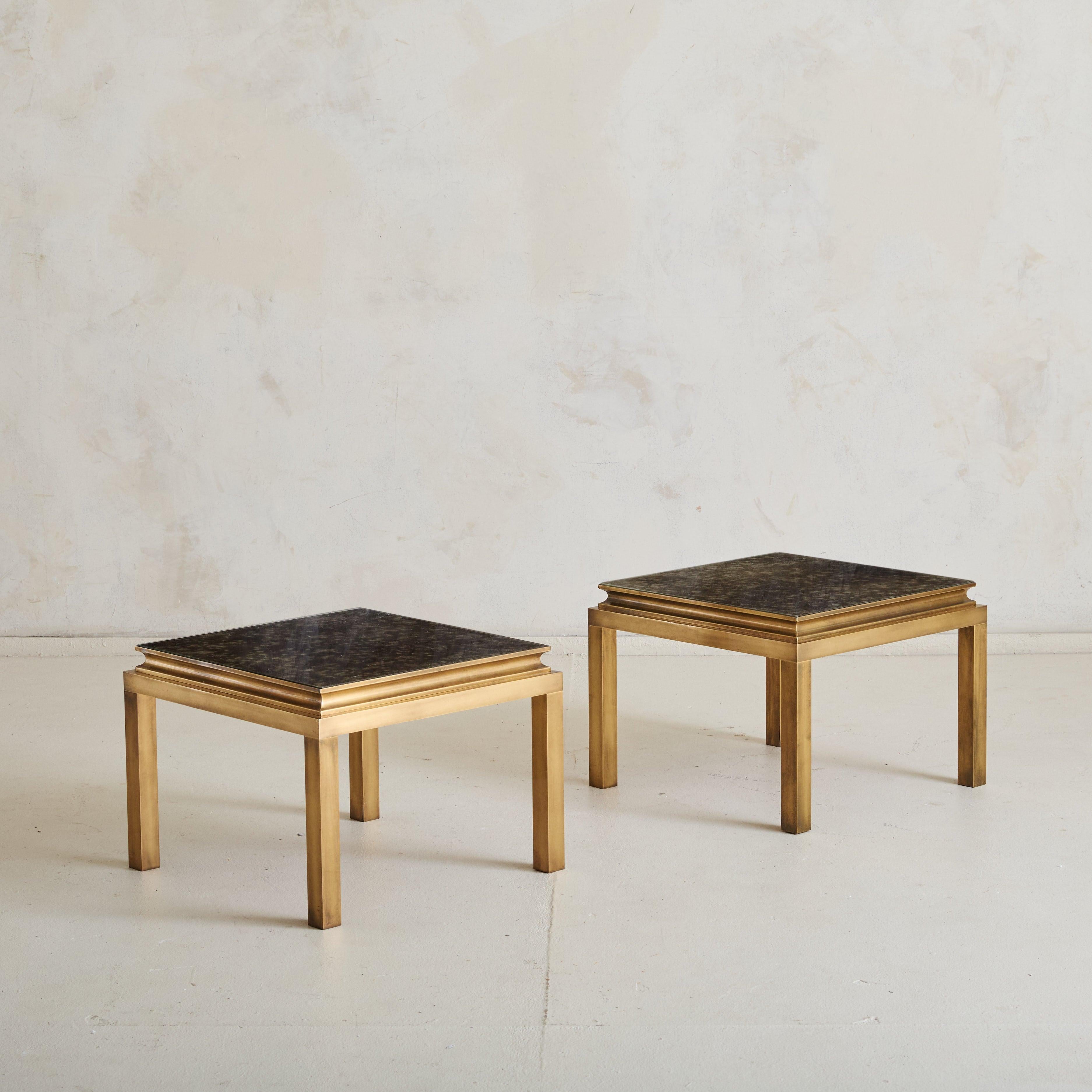 A small square side table from the 1960s, attributed to renowned designer Guy Lefevre for Maison Jansen. This table features an elegant polished brass frame in a luxurious finish, complemented by an églomisé mirror glass top. It functions