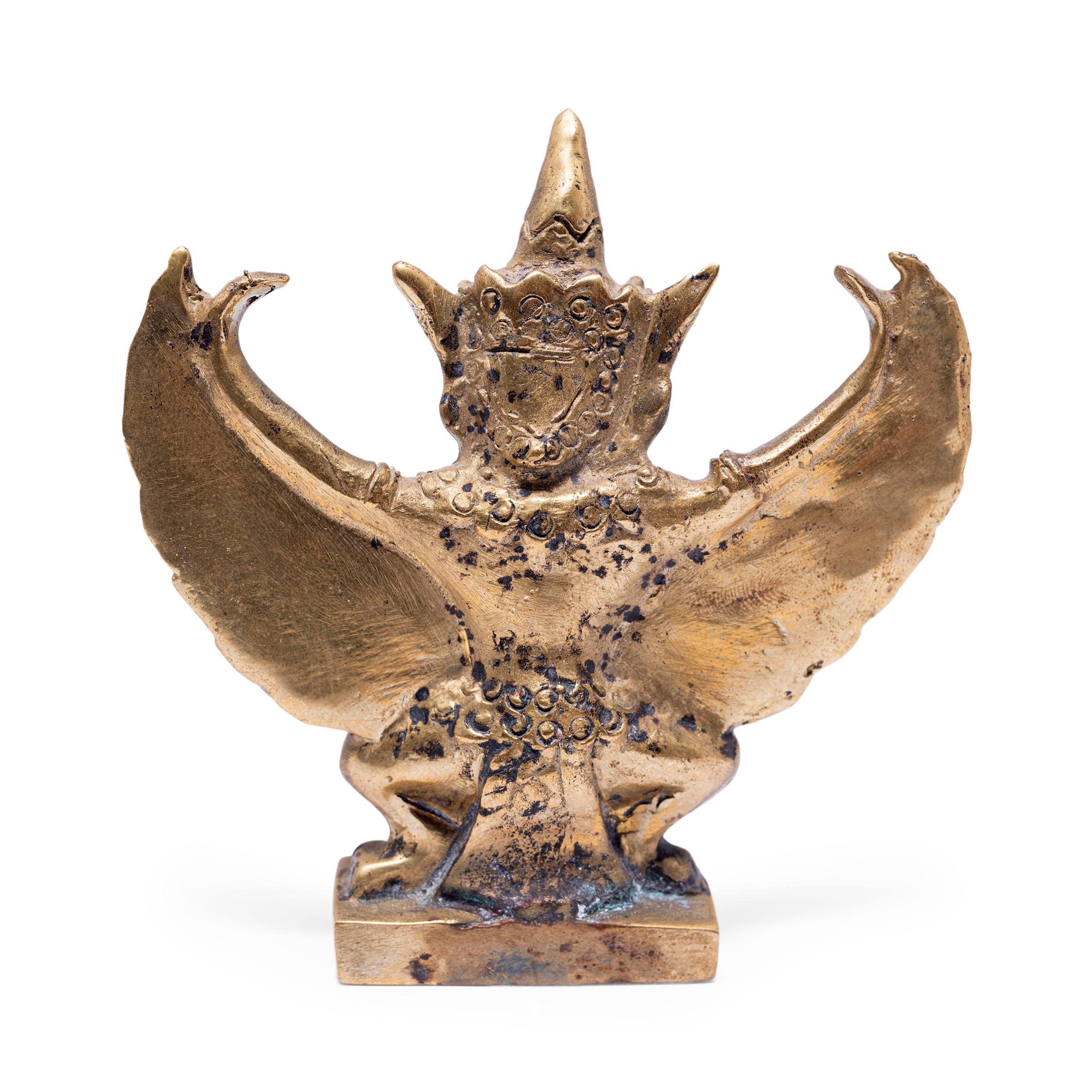 This petite bronze figurine is cast in the form of Garuda, a demigod and mythical king of birds in Hindu and Buddhist faith. Taking the form of half-bird half man, Garuda is a powerful protector and ever-watchful enemy of the serpent. Garuda is
