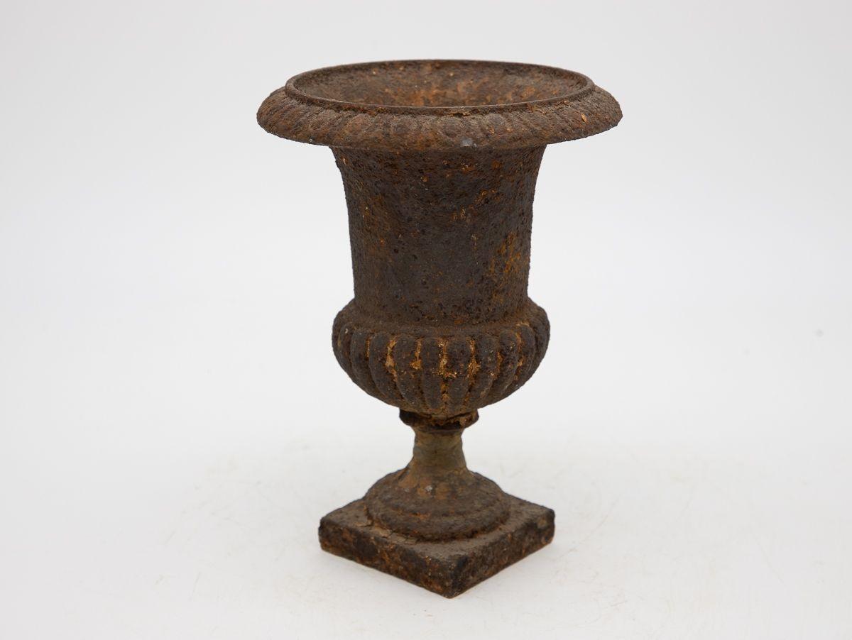 An early 20th-century black cast iron urn. This urn features an egg and dart pattern on the top rim and a fluted bottom on a square base. Some paint loss, rust spots, wear consistent with age and use.