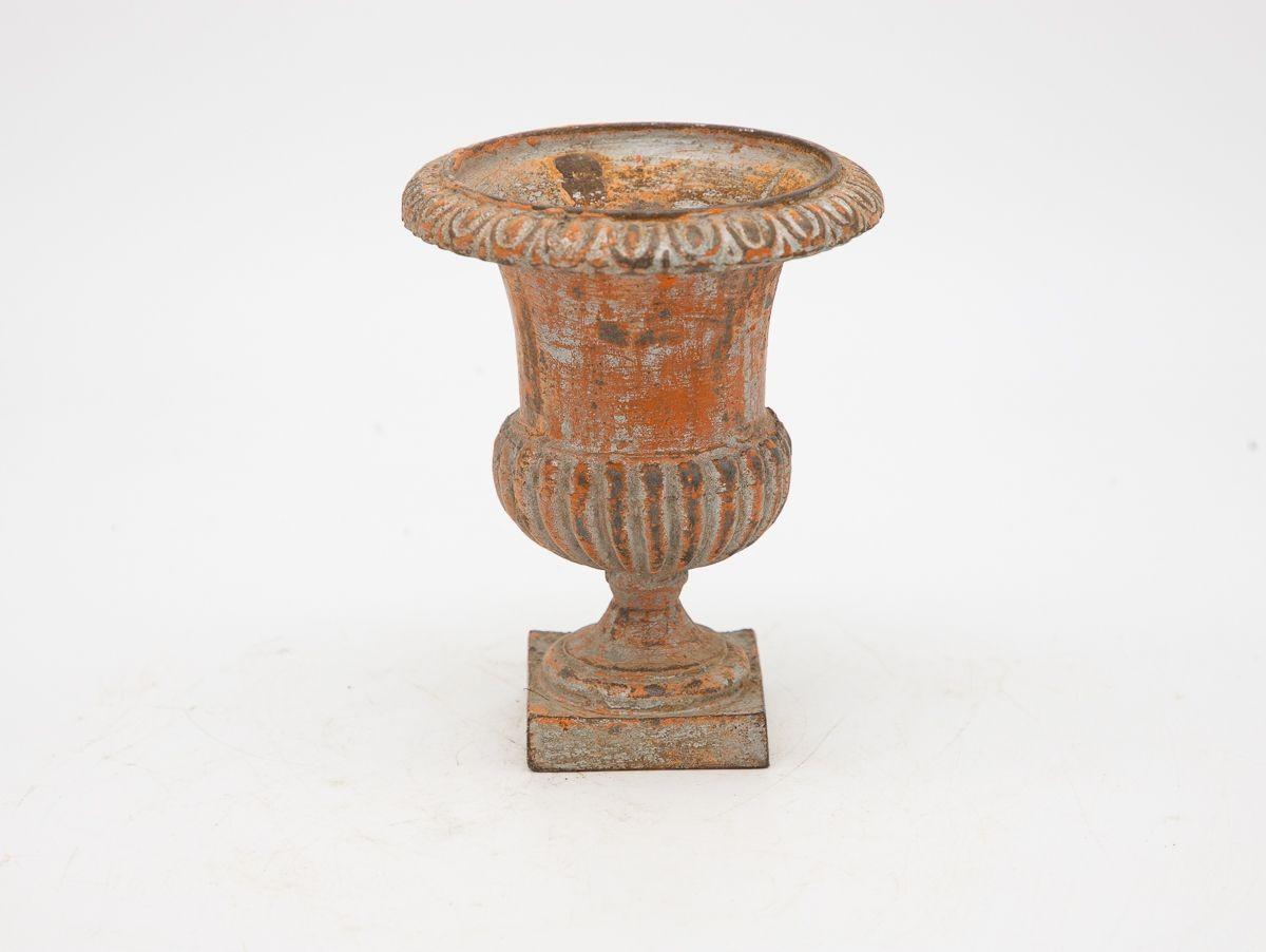 A mid-20th century grey painted cast iron urn. This urn features an egg and dart pattern on the top rim and a fluted bottom on a square base. Some paint loss, rust spots, wear consistent with age and use.