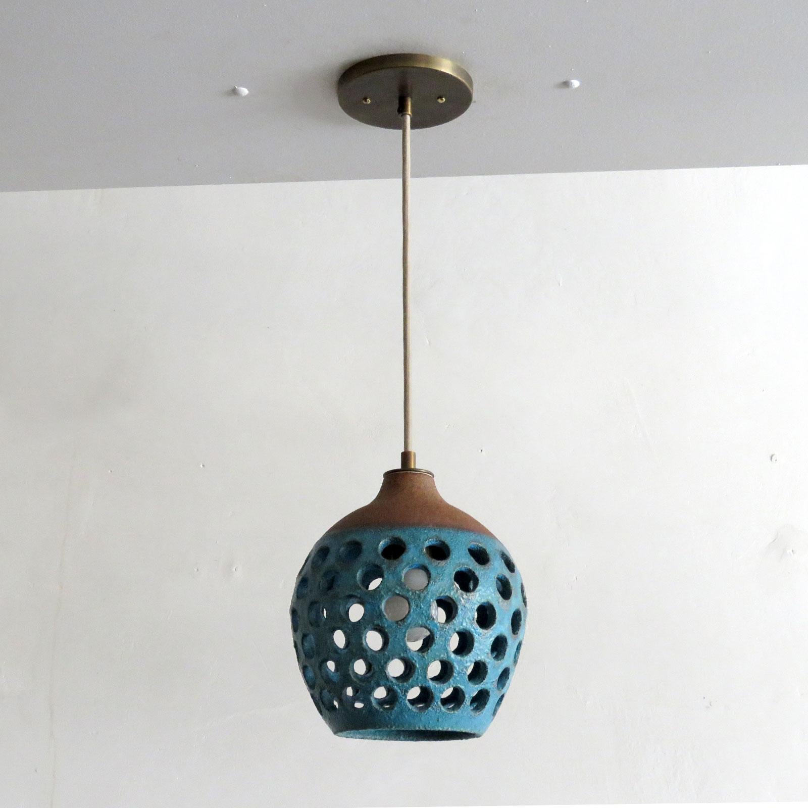 Wonderful petite ceramic pendant light No.1202, designed and handcrafted by Los Angeles based ceramicist Heather Levine. High fired stoneware with matte Turquoise glaze on cork colored clay body with decorative shapes cut out to expose light in