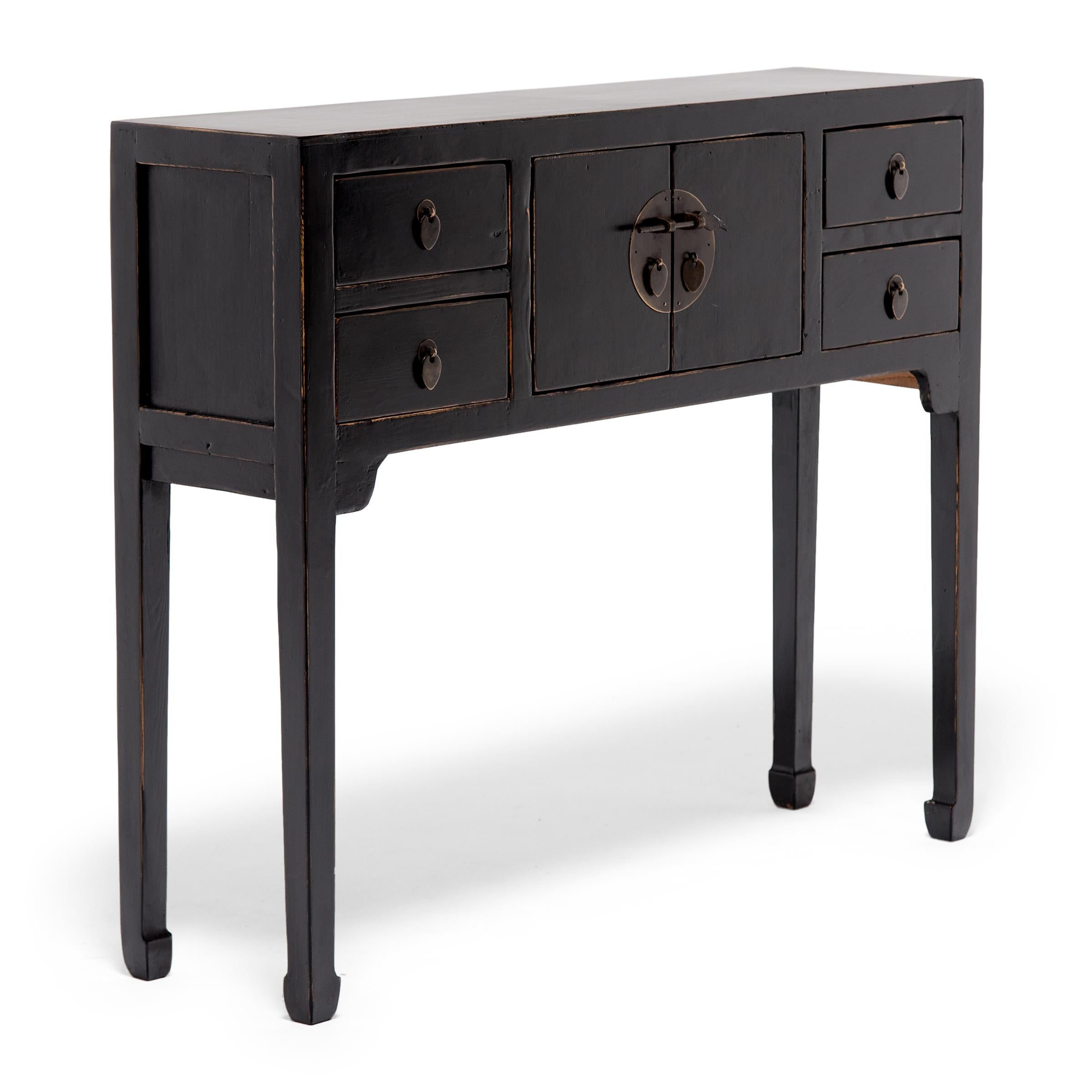 This black lacquer altar coffer keeps with the style of Ming-dynasty furniture through its clean lines and minimal ornamentation. The slim legs and delicate hoof feet bring the eye upwards the squared frame and contribute to the effortless