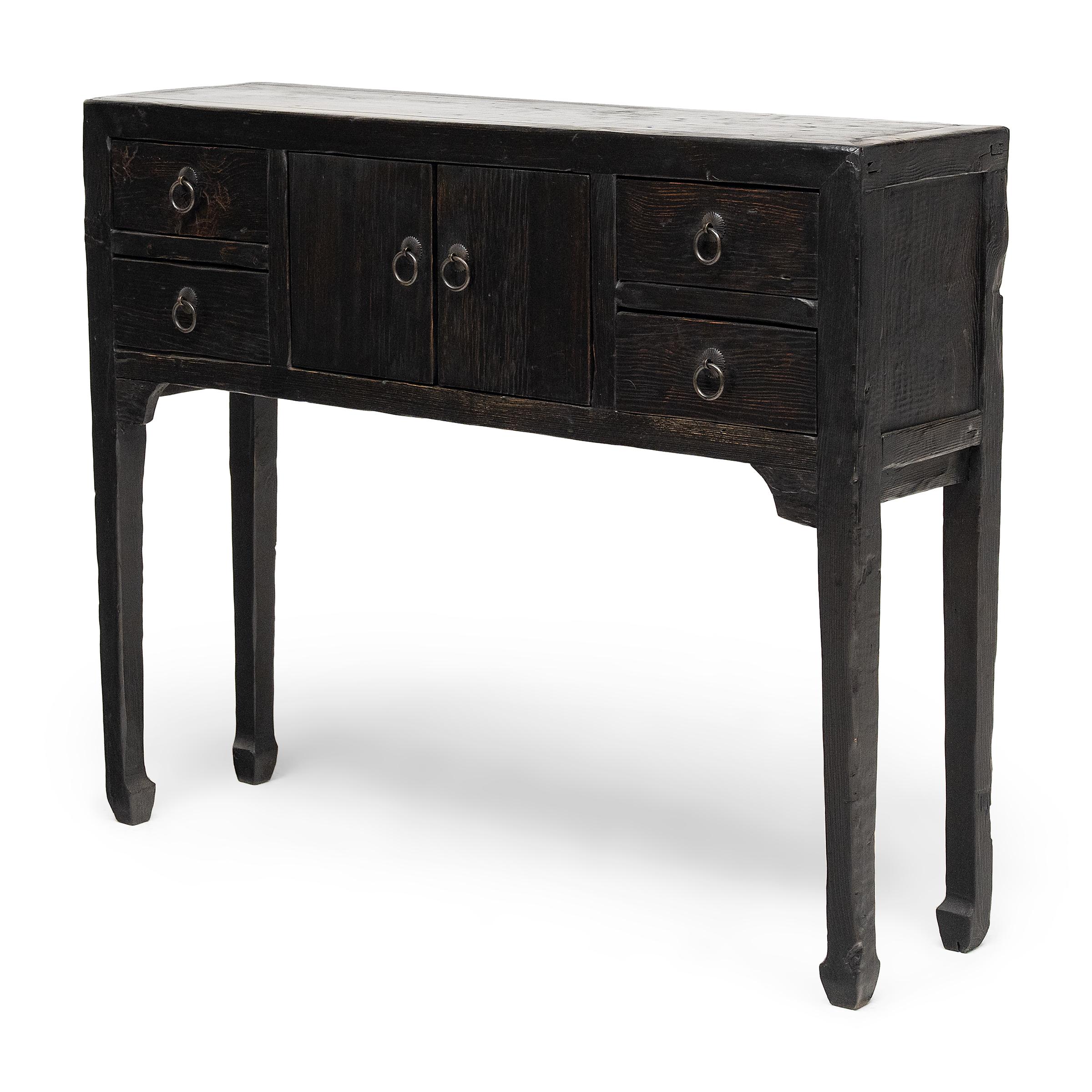 This petite altar coffer keeps with the style of Ming-dynasty furniture with clean lines and minimal ornamentation. Crafted of reclaimed wood with a black finish, the narrow table stands on thin legs ending in subtle hoof feet, focusing the eye