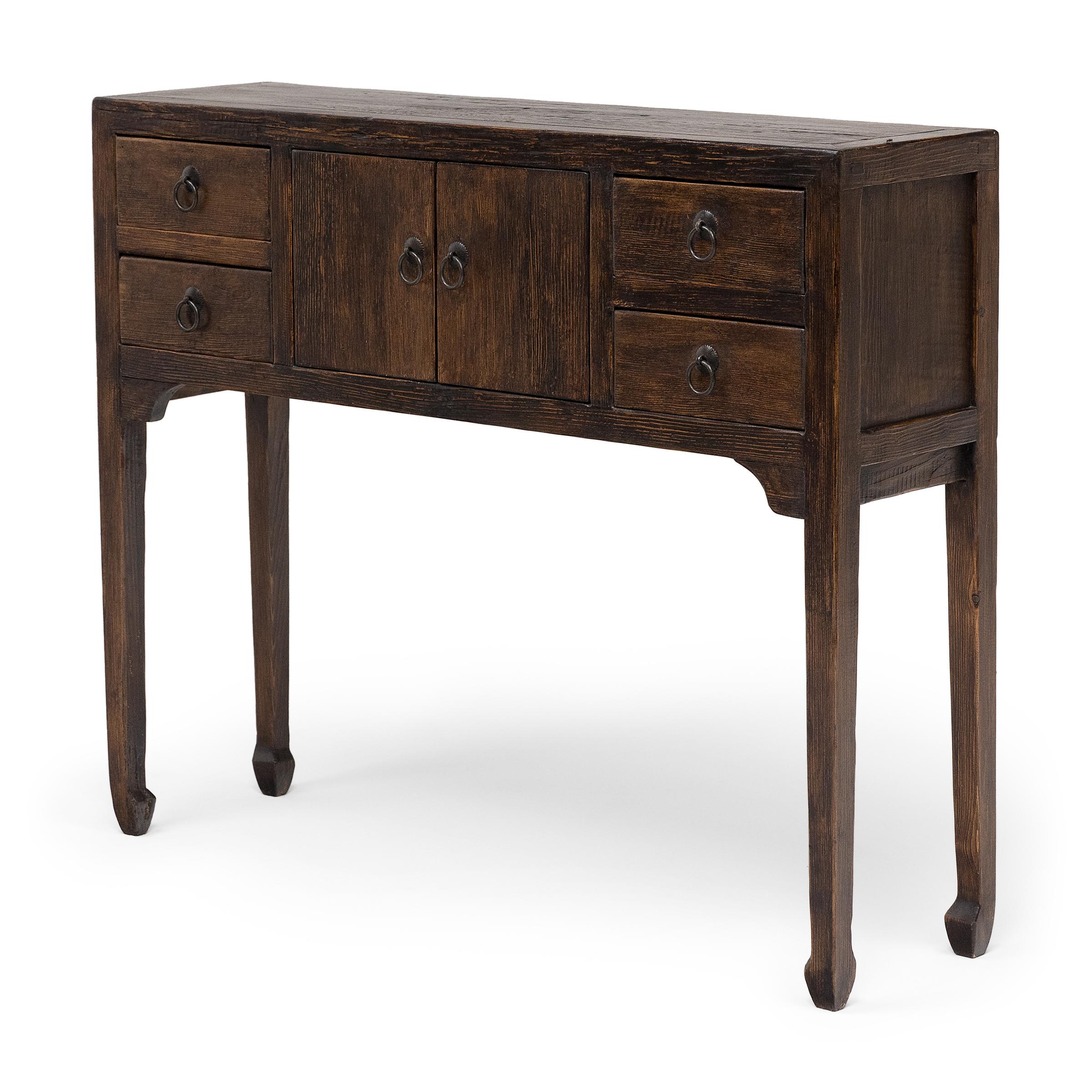 Este pequeño cofre de altar mantiene el estilo de los muebles de la dinastía Ming, con líneas limpias y mínima ornamentación. Fabricada en madera recuperada con un acabado marrón oscuro, la estrecha mesa se alza sobre finas patas acabadas en sutiles