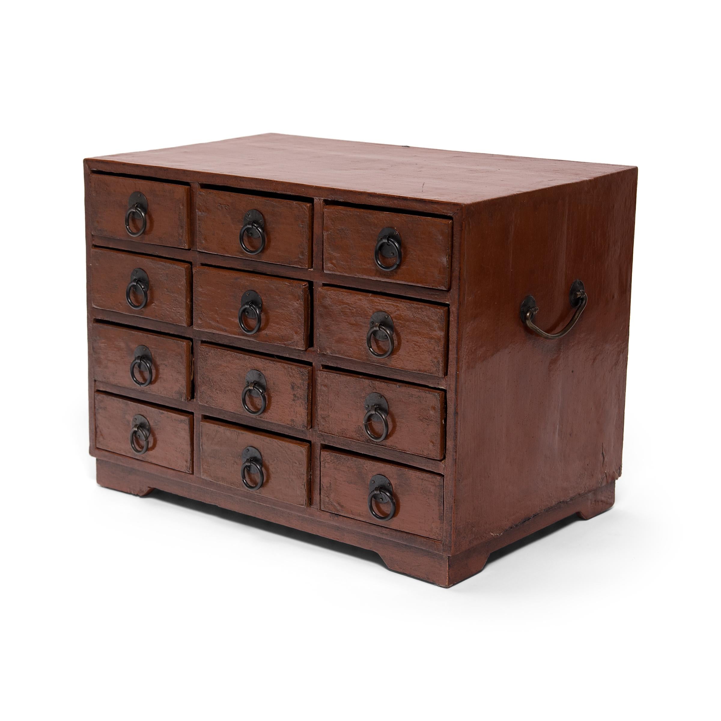 This early 20th century petite chest of drawers is an example of the multifunctional boxes used tabletop in lieu of a larger cabinets. Such boxes were used to store cosmetics, jewelry, documents, and other accessories. This chest clearly borrows its