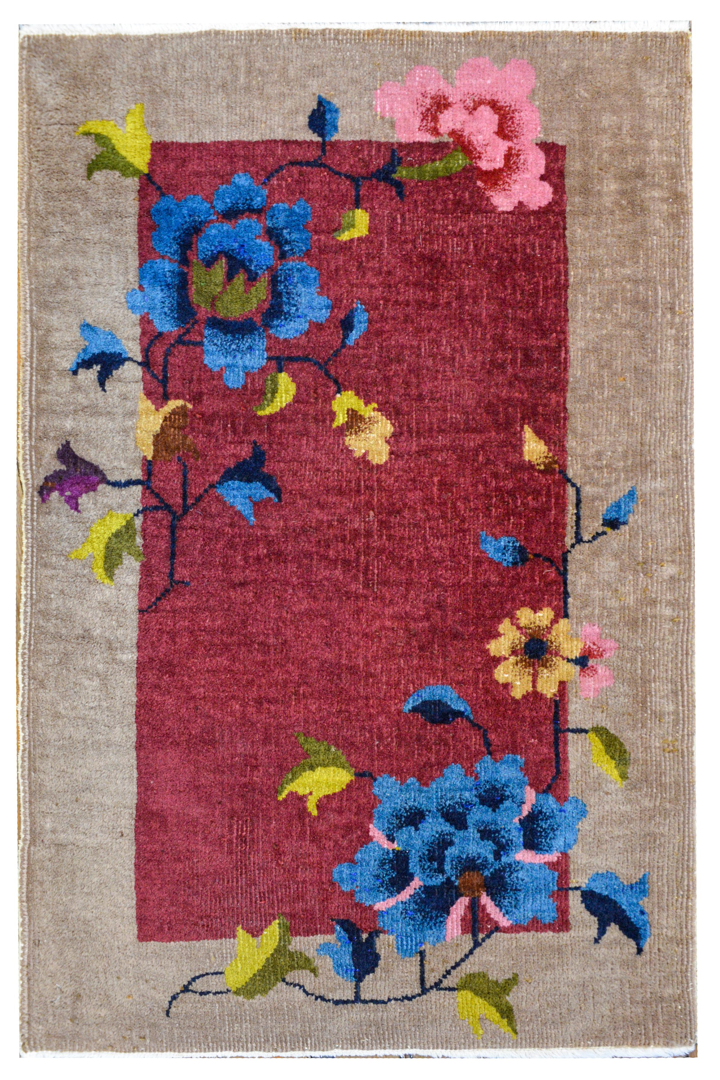 A petite Chinese Art Deco rug with a solid dark cranberry field surrounded by a wide gray border, and all overlaid with a multicolored peony pattern.