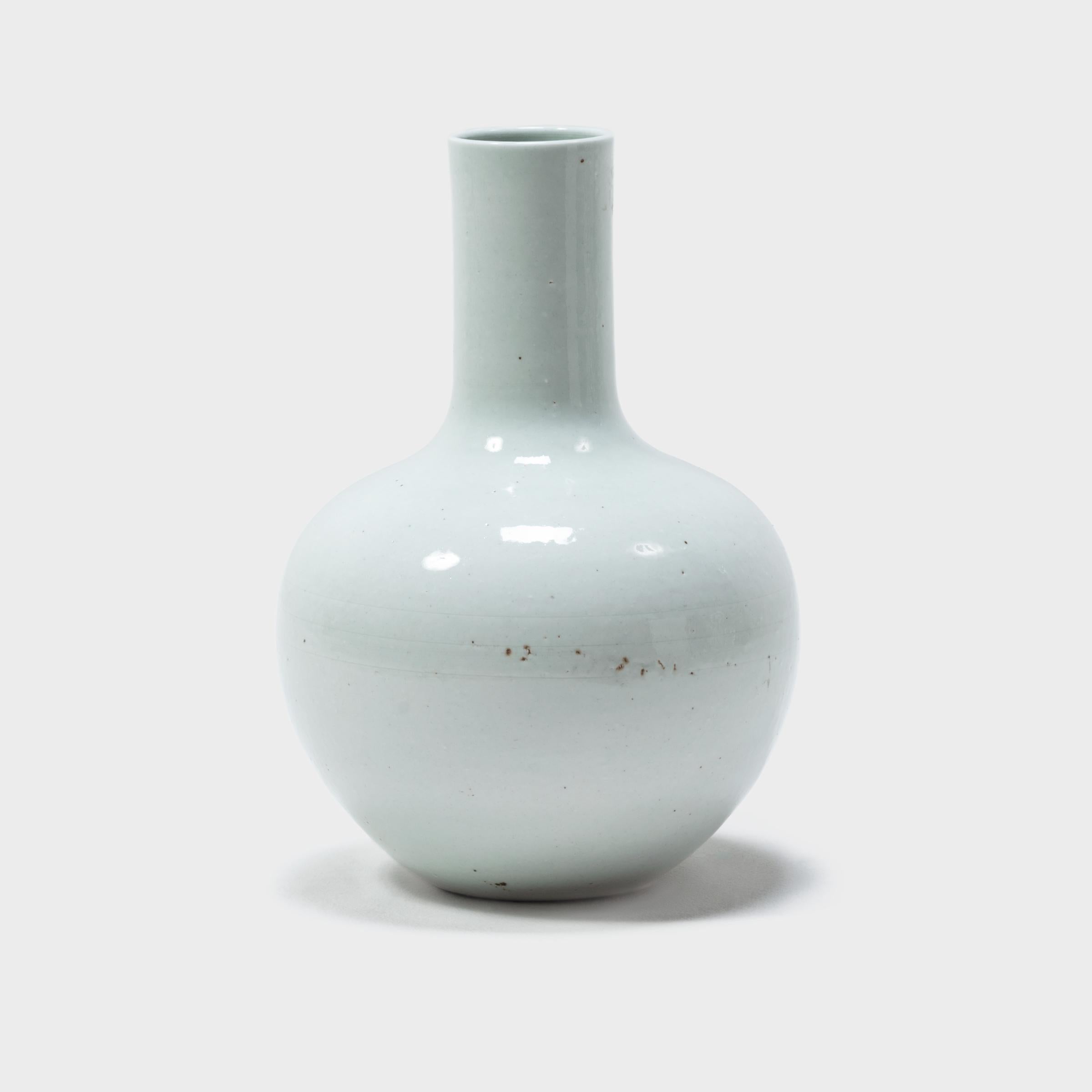 Drawing on a long Chinese tradition of monochrome ceramics, this austere long-necked vase is glazed in serene, cloud-inspired white. Crafted in Jiangxi province, local ceramists reinterpreted this traditional gooseneck shape with clean lines and an