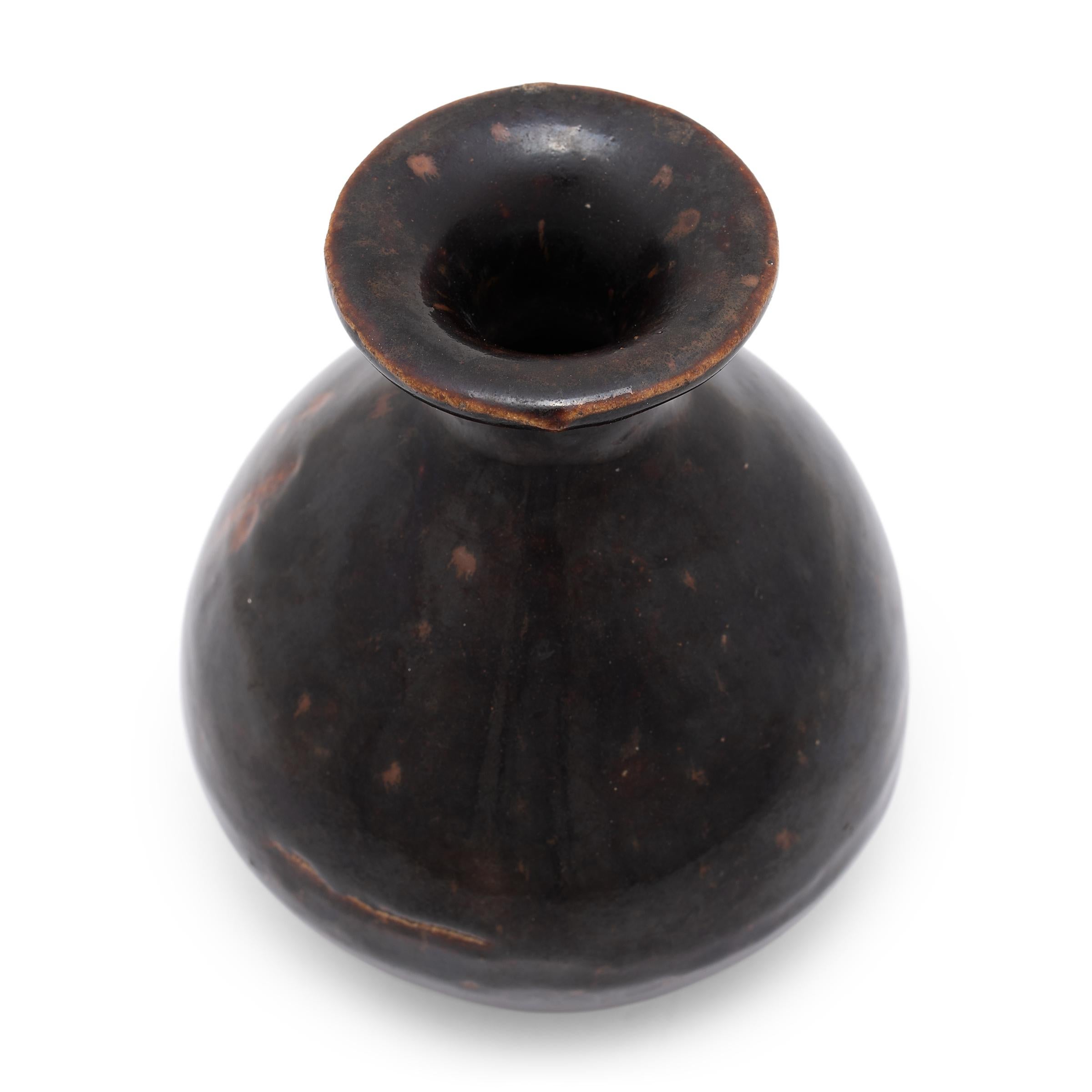 This 19th-century wine jar is cloaked inside and out with a rich, dark brown glaze that sheets across its rounded form, lingering beautifully on every imperfection. The jar's sculptural shape is known as a yuhuchunping or pear-shaped vase, defined