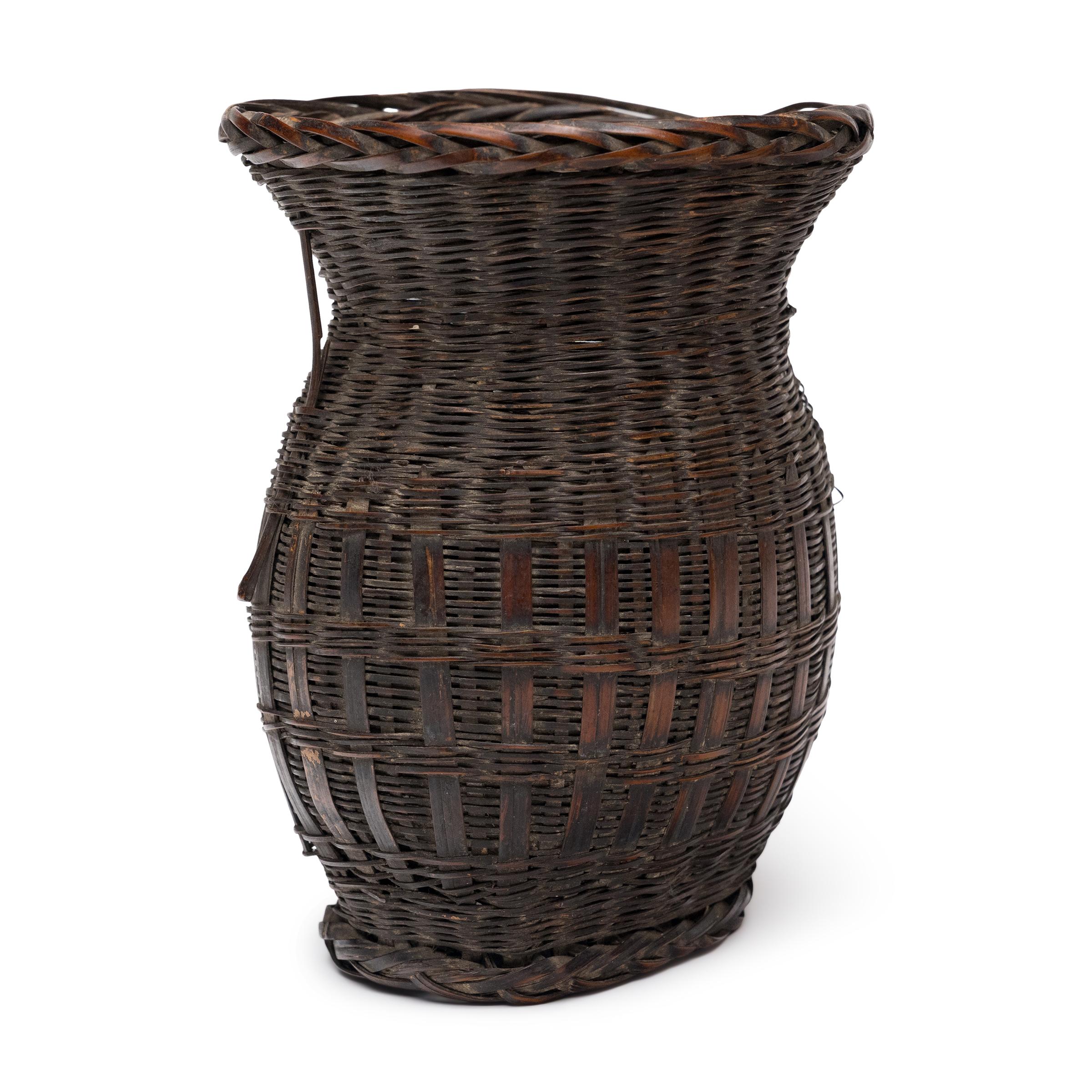 Intrecciato con una scala preziosa e un'arte delicata, questo piccolo cesto di bambù dell'inizio del XX secolo è un bellissimo esempio di cesteria tradizionale cinese. Realizzato a mano nel sud-ovest della Cina, il piccolo cesto portatile veniva