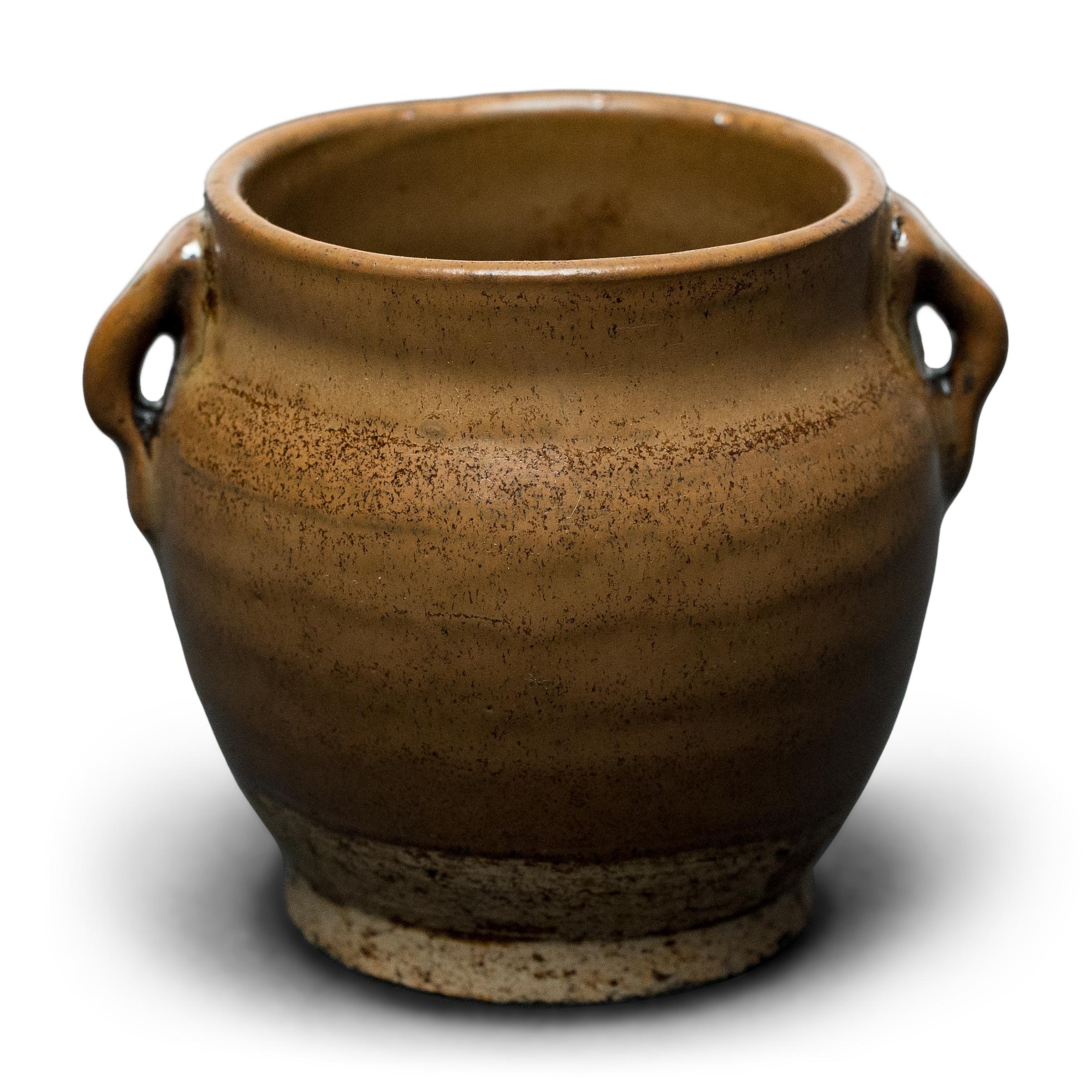This petite glazed jar from China's Shanxi province exemplifies the timeless appeal of handcrafted pottery. Once used in an apothecary to hold ground herbs and oils for traditional medicines, the little jar charms with precious scale and a light