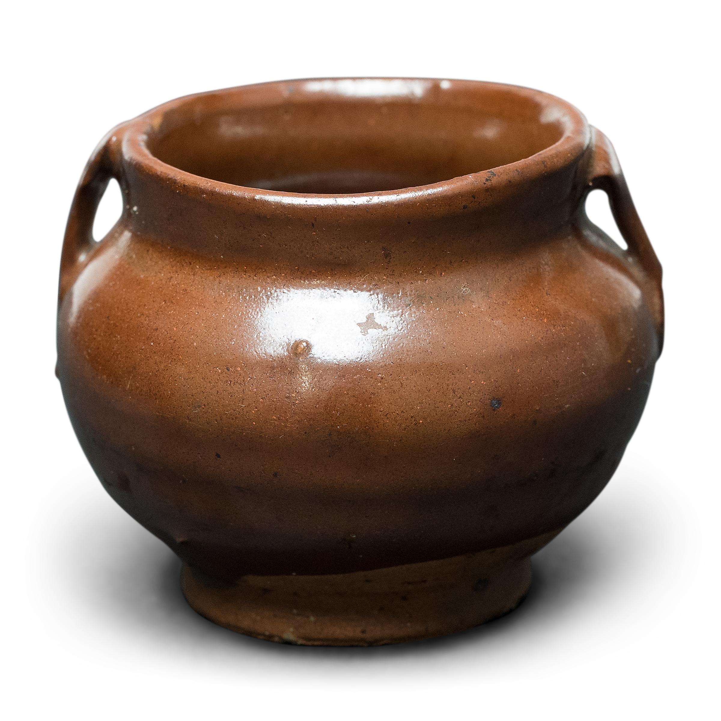 This petite glazed jar from China's Shanxi province exemplifies the timeless appeal of handcrafted pottery. Once used in an apothecary to hold ground herbs and oils for traditional medicines, the little jar charms with precious scale and a glossy,