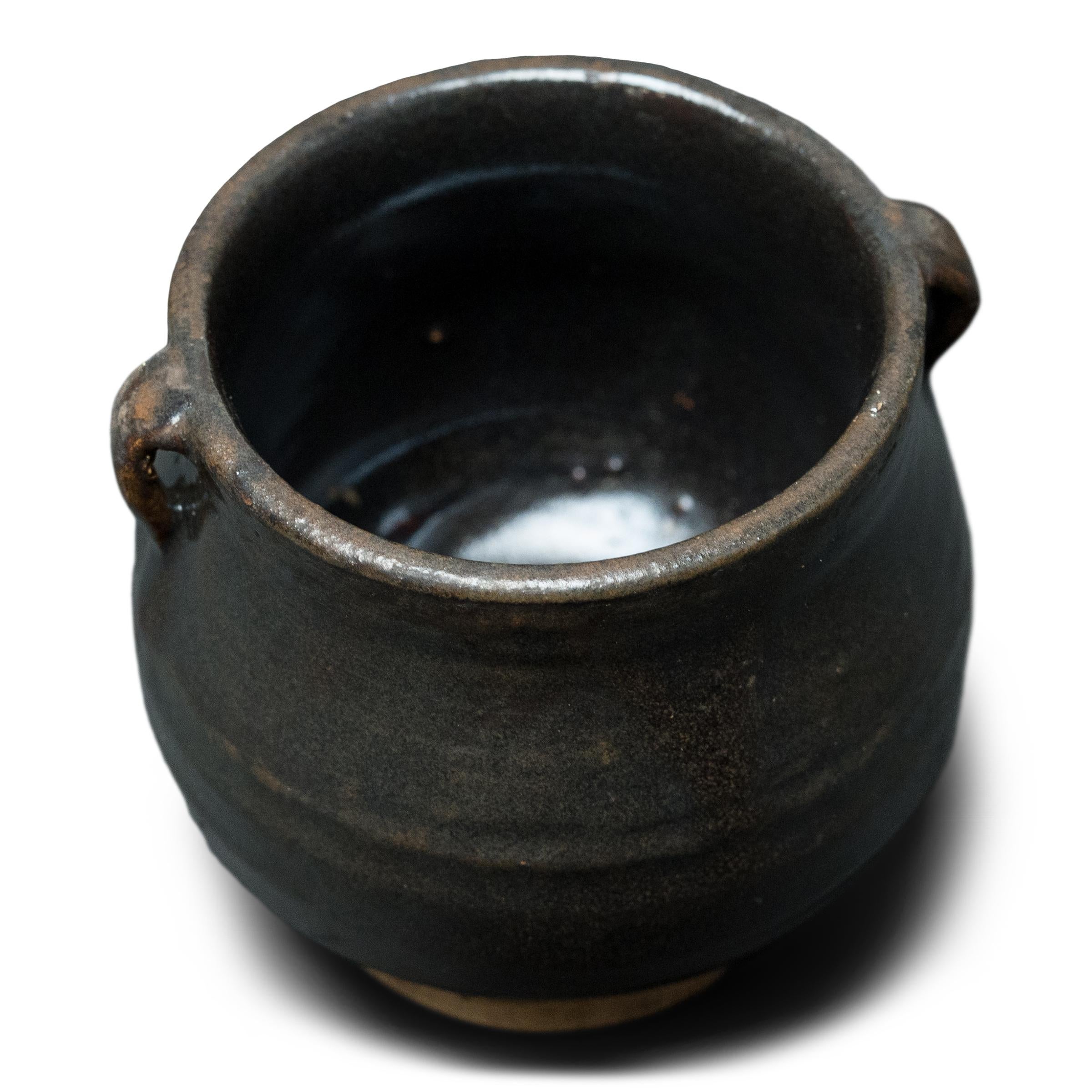 This petite glazed jar from China's Shanxi province exemplifies the timeless appeal of handcrafted pottery. Once used in an apothecary to hold ground herbs and oils for traditional medicines, the little jar charms with precious scale and a