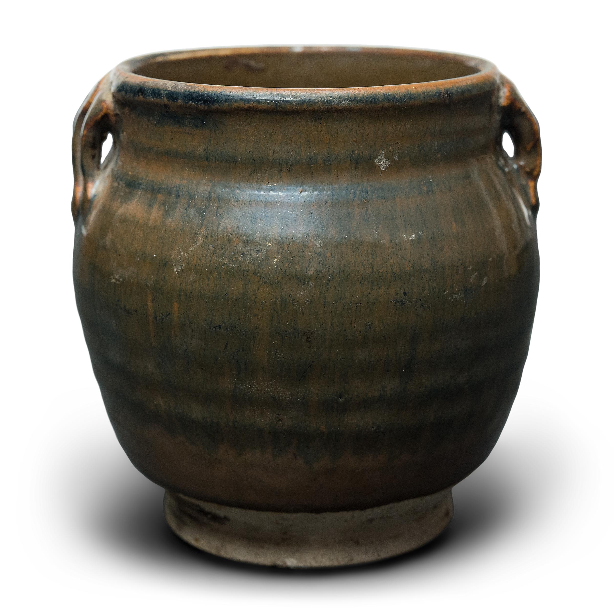 This small glazed jar from China's Shanxi province exemplifies the timeless appeal of handcrafted pottery. Once used in an apothecary to hold ground herbs and oils for traditional medicines, the jar charms with precious scale and a beautifully