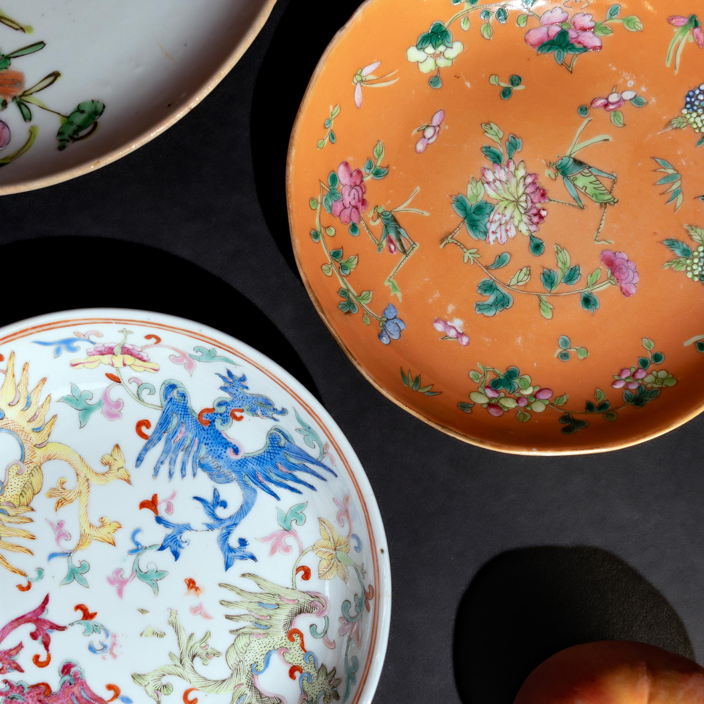 This petite porcelain dish from the late Qing-dynasty (1644-1911) has a whimsical design of peonies, begonias and plum blossoms, hand-painted with famille rose enamels and set against a soft orange field. The charming garden scene is dotted with