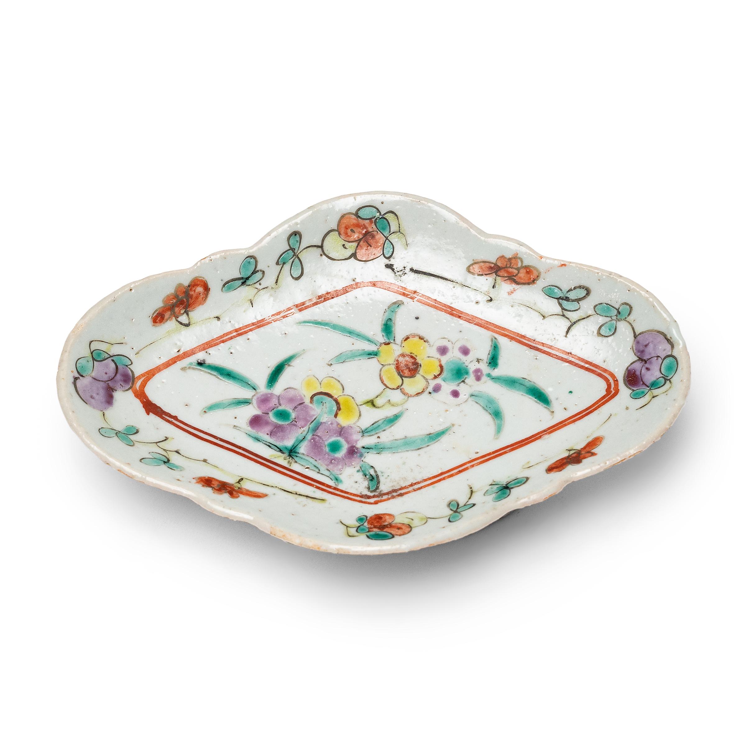 Ce charmant plat en porcelaine datant du début du 20e siècle est décoré d'émaux surglacés colorés dans le style de la famille rose. Probablement utilisé comme plat de service pour les offrandes alimentaires rituelles, ce petit bol a une forme