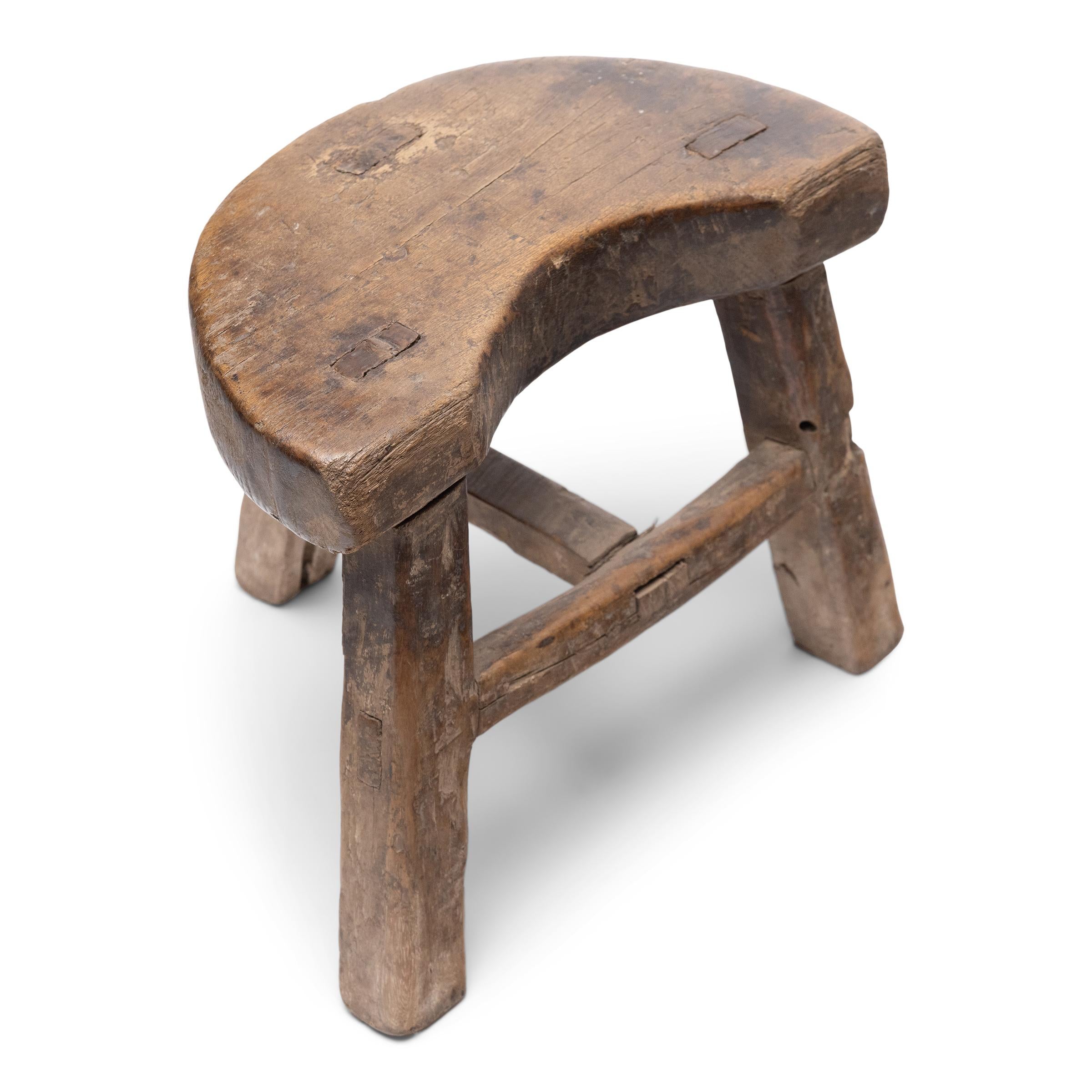 With rustic texture and simplicity of form, this petite 19th-century stool is a timeless example of casual seating in rural China. Crafted of northern elm (yumu) with mortise-and-tenon joinery, the low stool features a unique seat shaped like a
