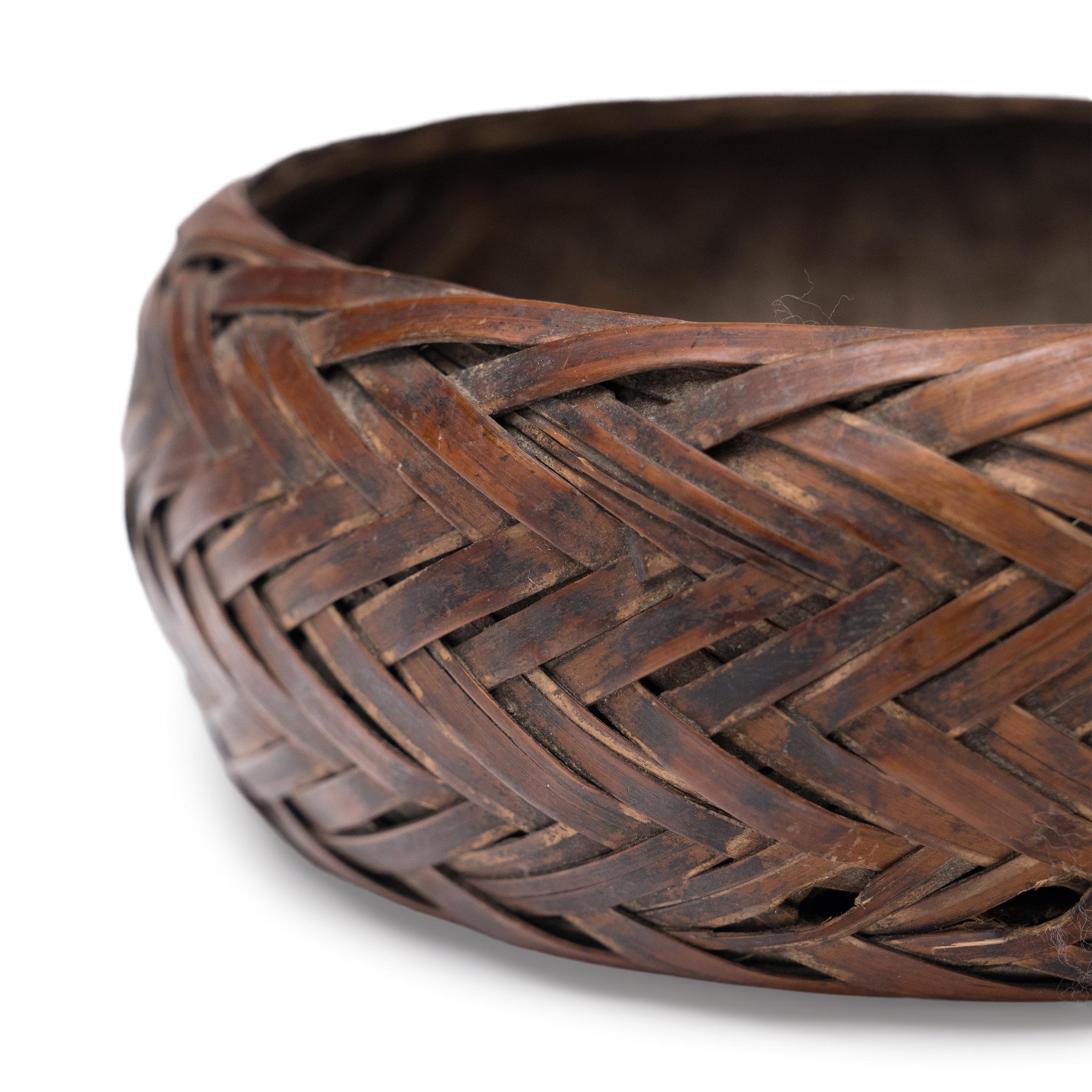 Dieser geflochtene Korb aus der Provinz Guizhou zeugt von der schönen Einfachheit eines handgeflochtenen Objekts. Das kunstvoll aus dünnen Bambusstreifen geflochtene Körbchen wurde ursprünglich für die Zubereitung und das Servieren von Portionen