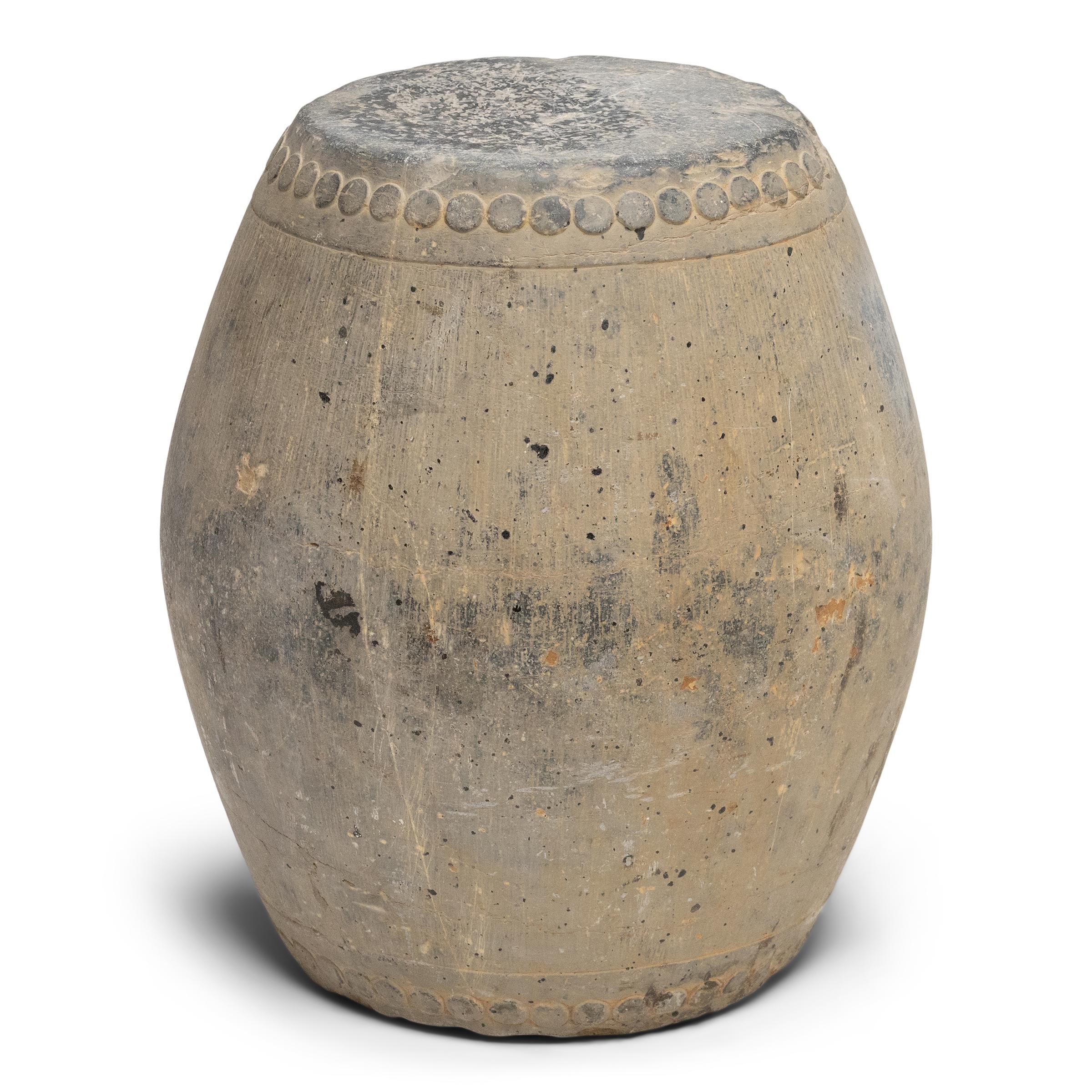 Esta mesa baja de exposición está esculpida a partir de un bloque macizo de piedra, tallado a mano según la forma tradicional de tambor de los taburetes de jardín chinos. Un anillo de círculos alrededor de la parte superior e inferior imita los