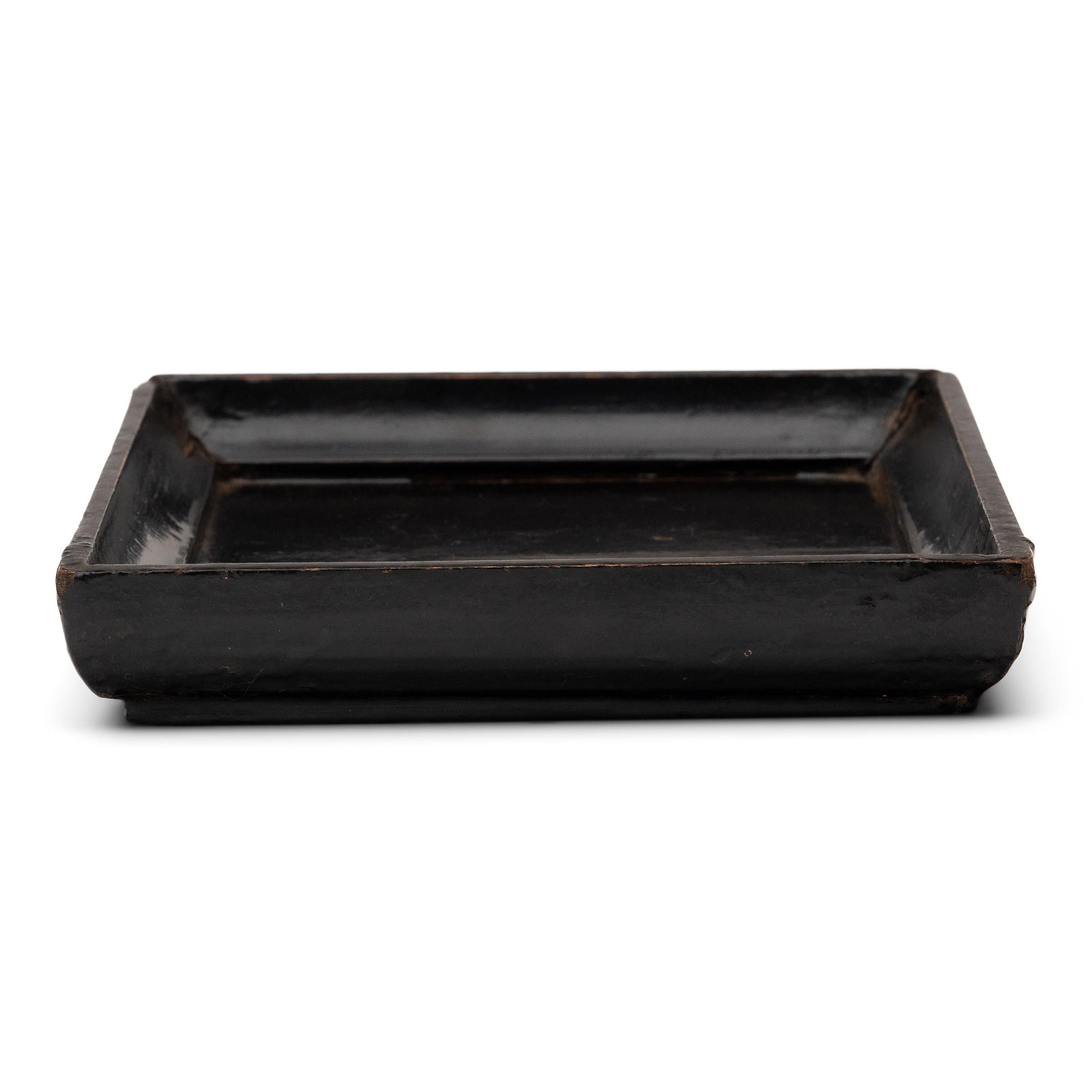 Des lignes simples, une forme modeste et une couche de laque brossée à la main confèrent à ce petit plateau de la dynastie Qing un charme provincial qui rappelle la chaleur du foyer. Riche en caractère, le plateau carré est fini avec une couche de