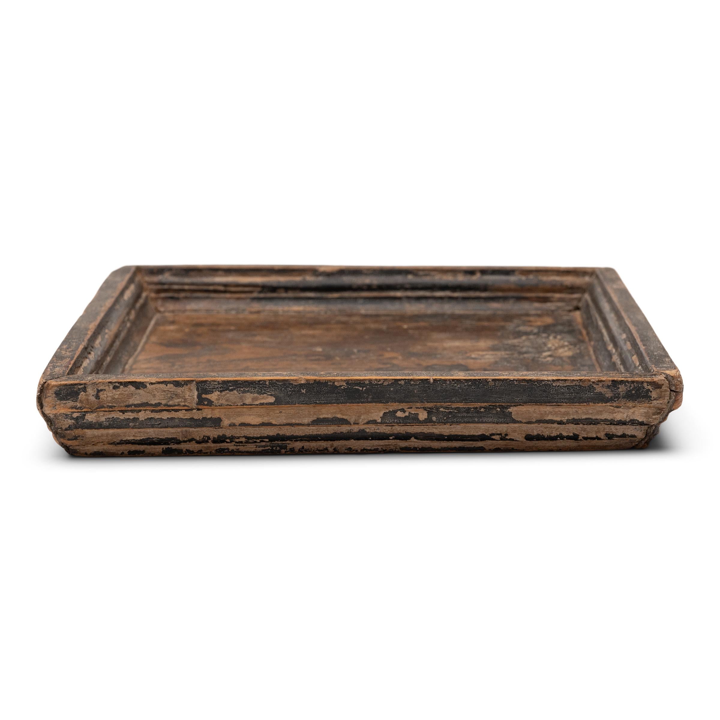 Simple lines, a modest form, and a layer of hand-brushed lacquer give this petite Qing-dynasty tray a provincial charm that recalls the warmth of home. The original black lacquer finish has weathered with time for a wabi-sabi feel, revealing the