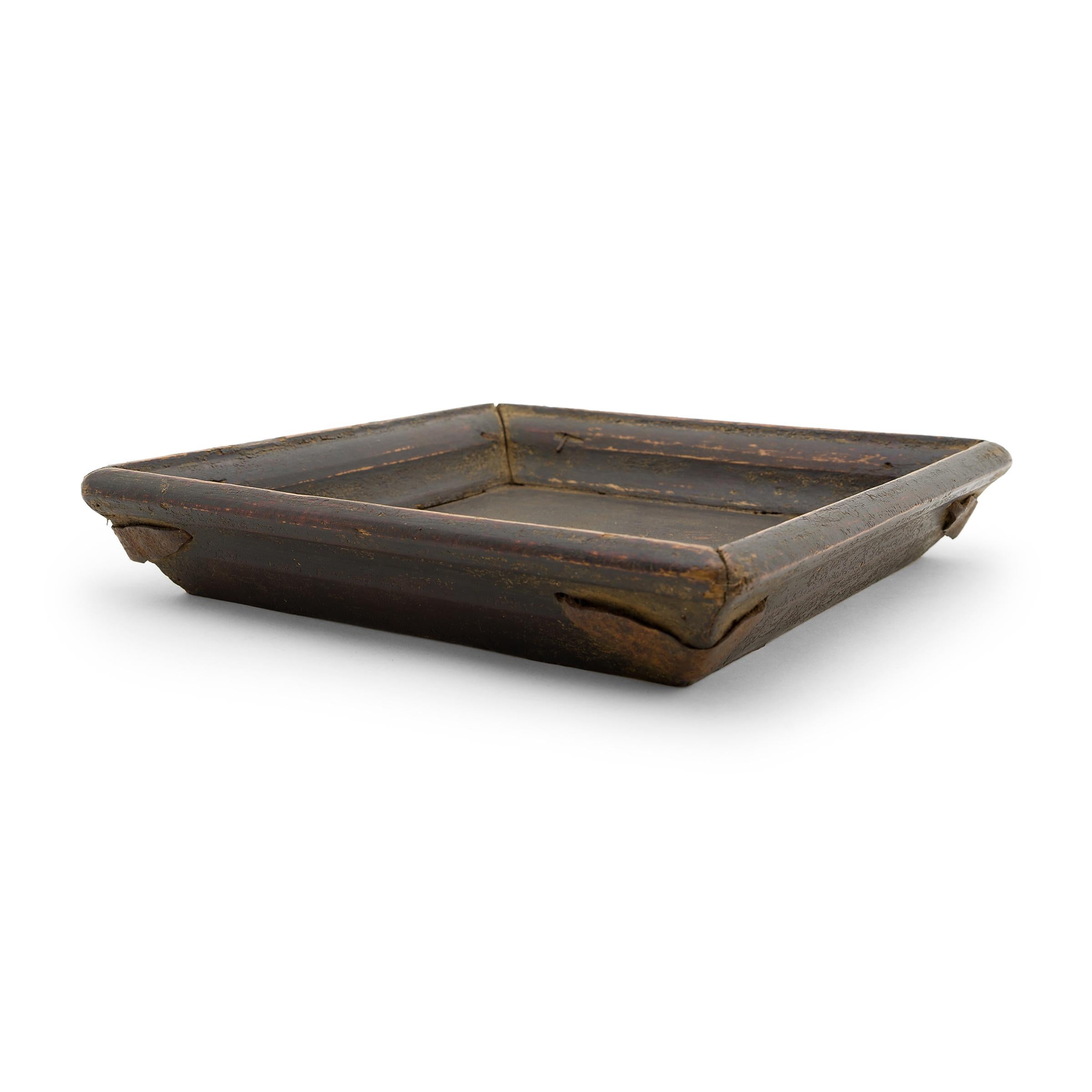 Simple lines, a modest form, and a layer of hand-brushed lacquer give this petite Qing-dynasty tray a provincial charm that recalls the warmth of home. The dark, red-brown lacquer finish has weathered with time to reveal the pine wood underneath and