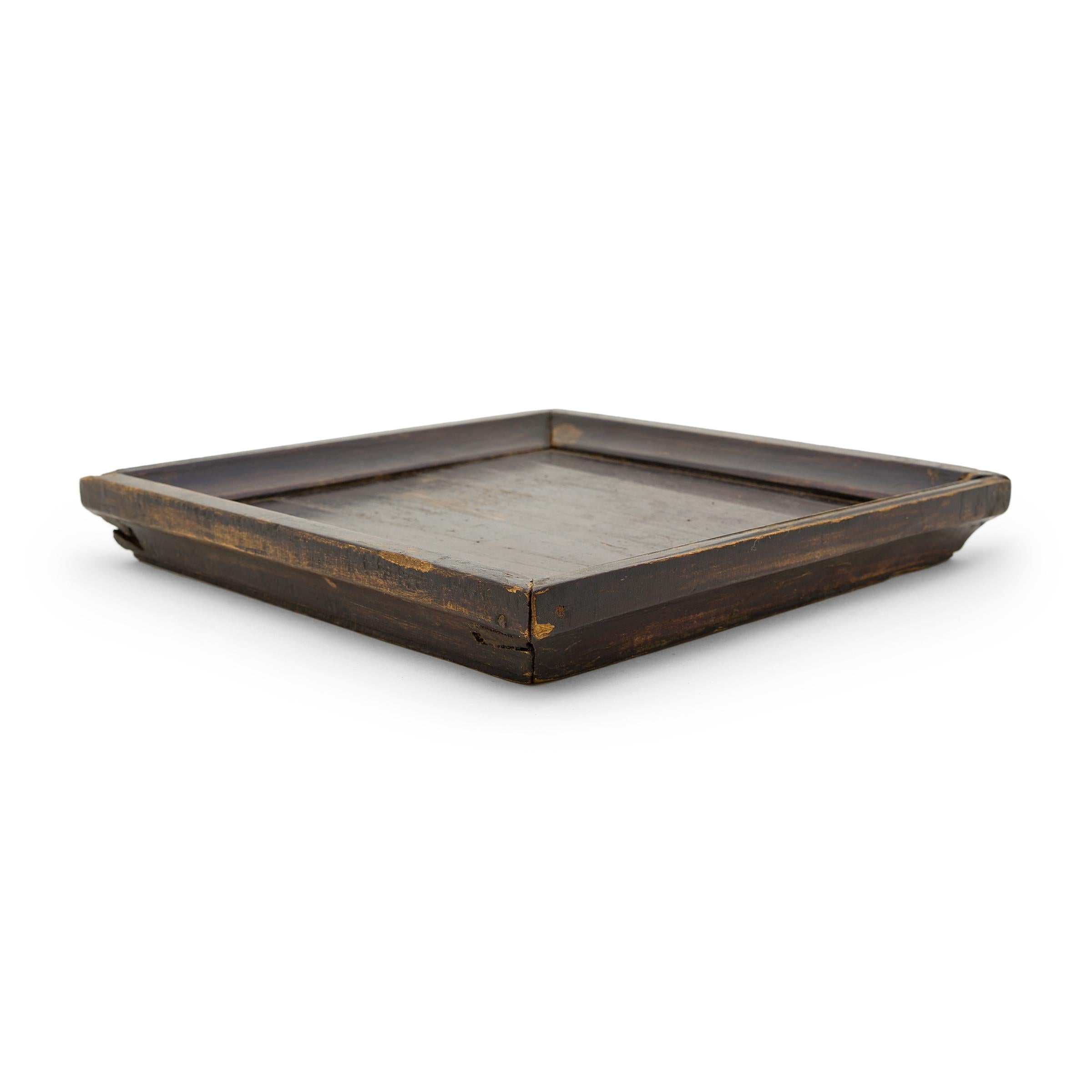Simple lines, a modest form, and a layer of hand-brushed lacquer give this petite Qing-dynasty tray a provincial charm that recalls the warmth of home. The dark, red-brown lacquer finish has weathered with time to reveal the light brown coloring of