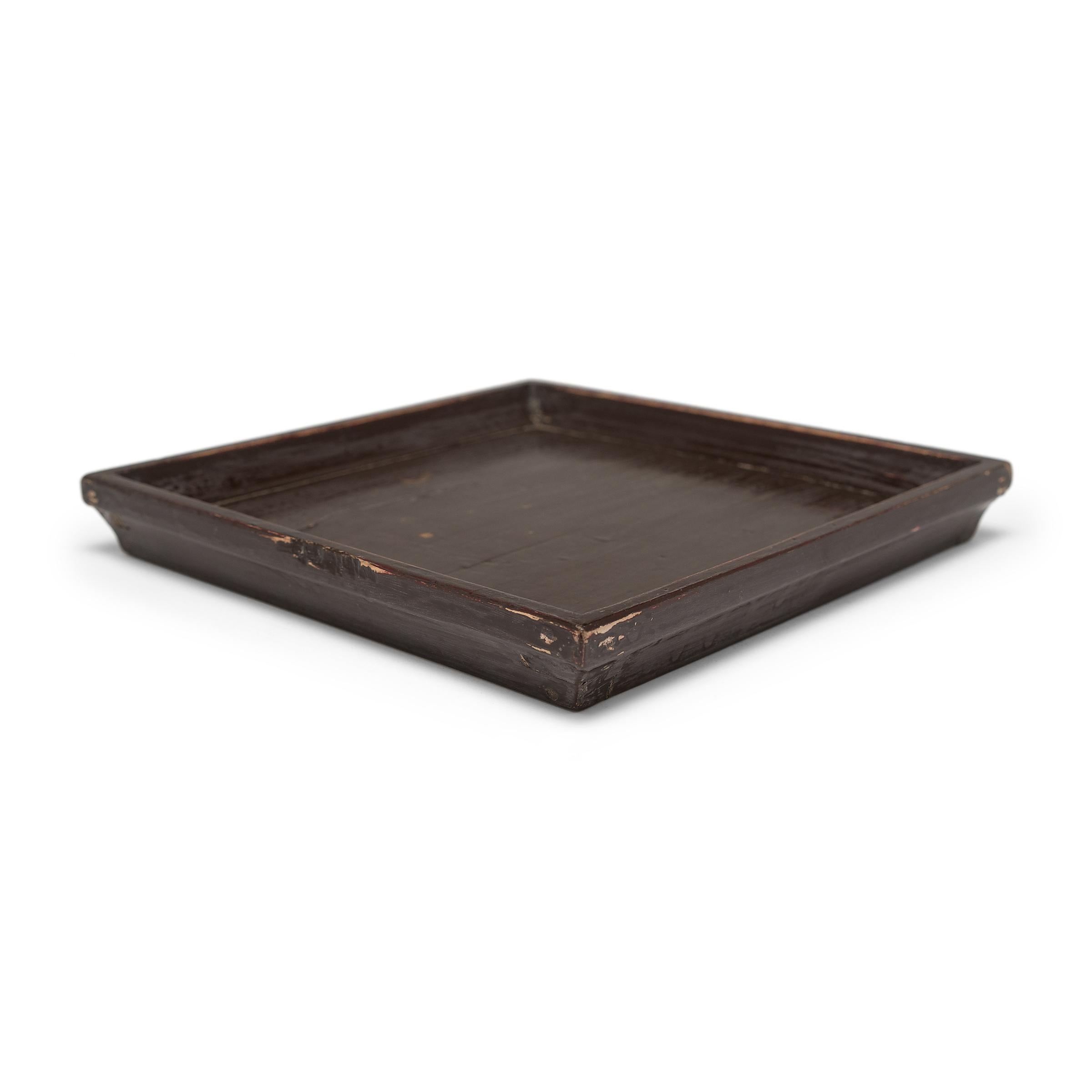 Simple lines, a modest form, and a layer of hand-brushed lacquer give this petite Qing-dynasty tray a provincial charm that recalls the warmth of home. The dark brown lacquer finish has weathered with time to reveal the light brown coloring of its