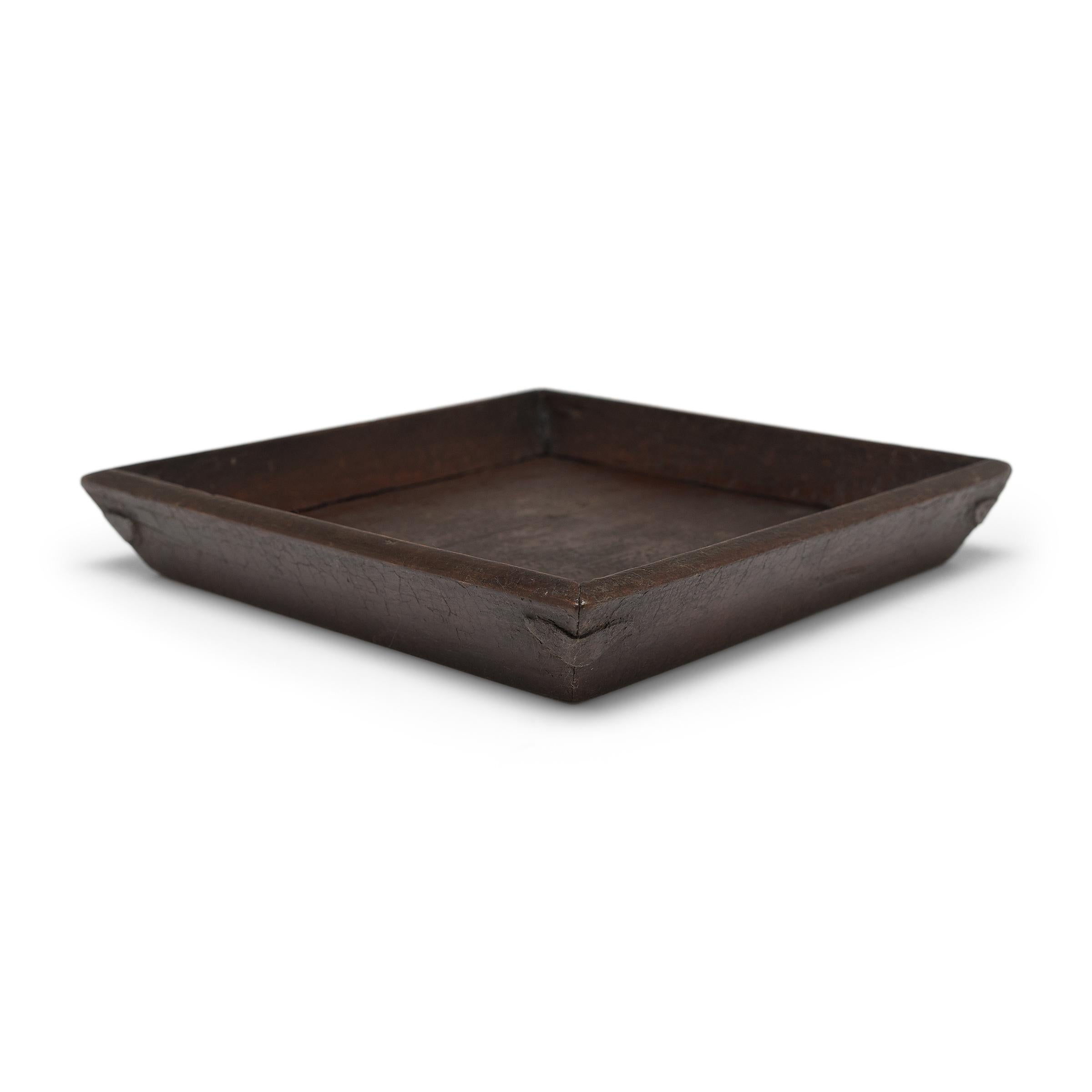 Simple lines, a modest form, and a layer of hand-brushed brown lacquer give this petite Qing-dynasty tray a provincial charm that recalls the warmth of home. A wooden tray like this would have been used to serve tea or food to friends and family