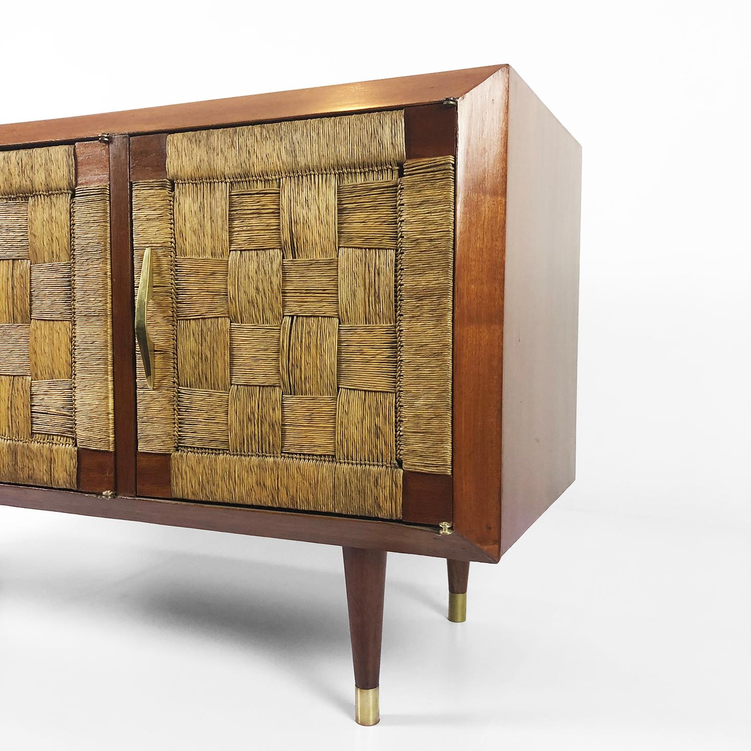 This piece of furniture has characteristics that suggest that it was designed by Edmond Spence for Industria Mueblera but does not include labels or brands, circa 1950.

A solid mahogany three-door credenza with brass legs and seagrass door
