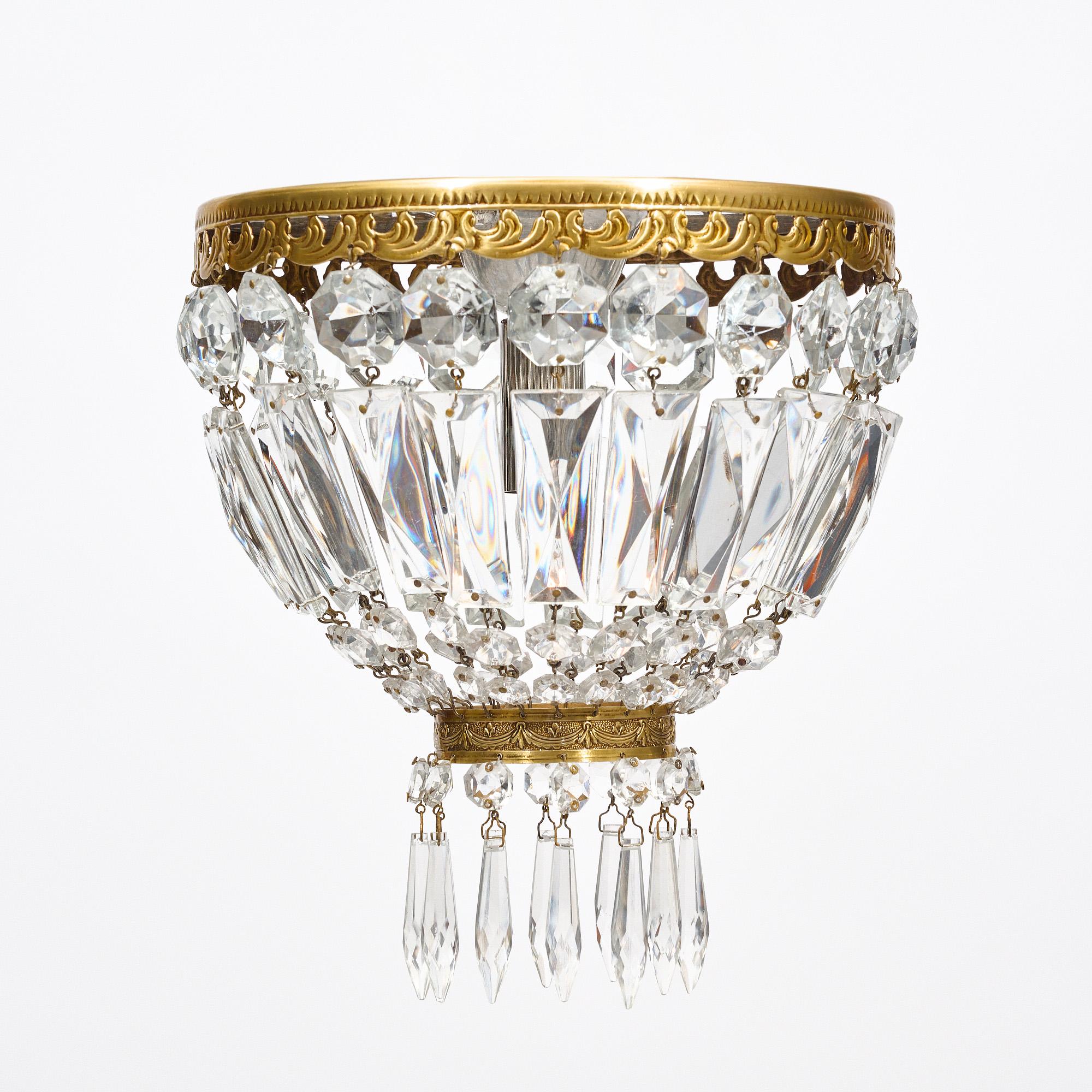 Paire de lustres en cristal de France présentant des brins de cristal taillé suspendus à des couronnes en laiton. Ils ont été nouvellement câblés pour répondre aux normes américaines.
