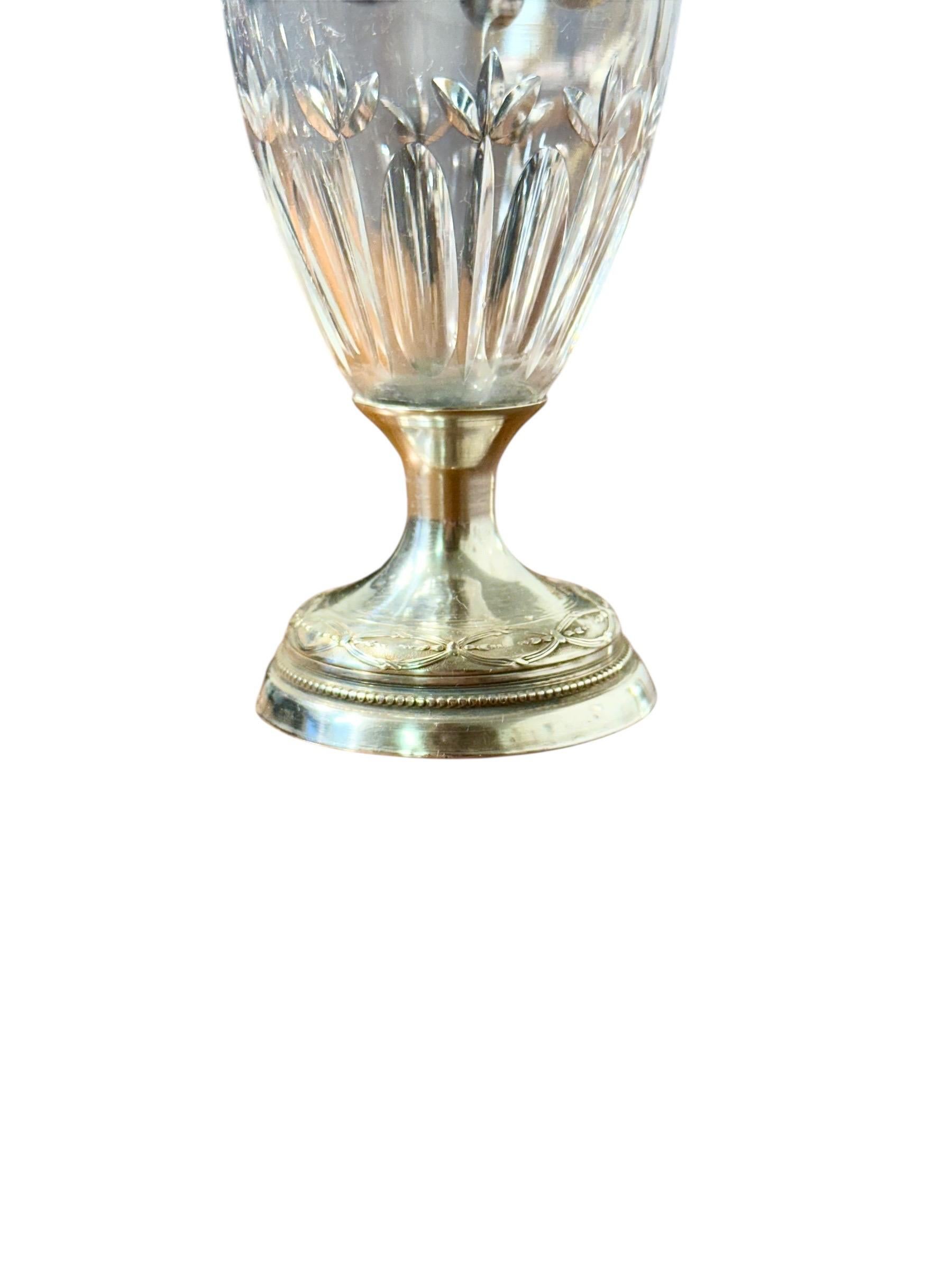 Questo raffinato vaso di cristallo francese, montato in argento massiccio con marchio Minerva (che indica argento di qualità 950/1000), è un delicato esempio di artigianato del primo Ottocento. Il corpo è splendidamente tagliato con scanalature