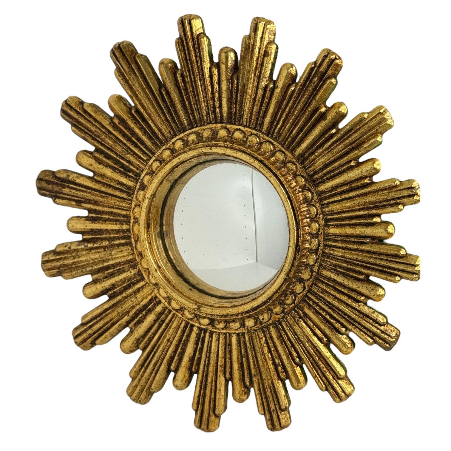 A petite starburst sunburst convex mirror. Made of gilded resin and wood. It measures approximate 9.5