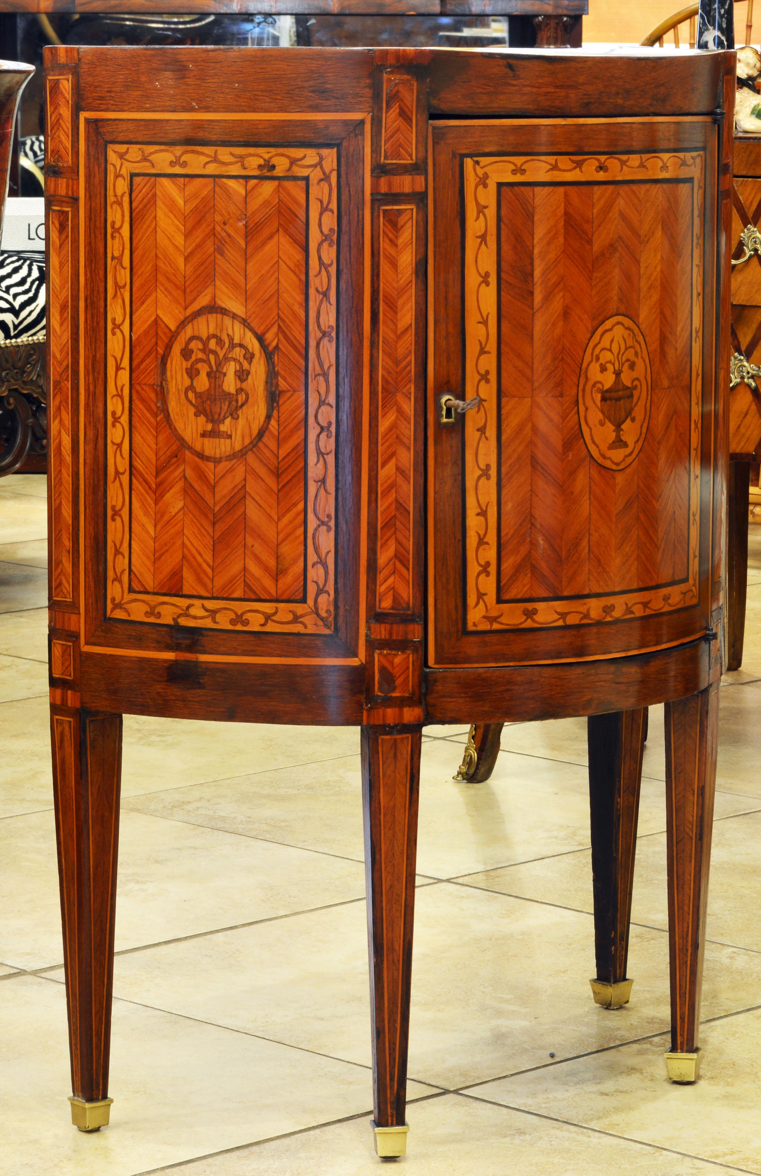 The caddy style top of this cabinet makes it extra attractive. The top is inlaid parquetry style and centering a classical urn motif typical of the Louis XVI style. The door and the flanking panels are similarly inlaid with parquetry, banding,