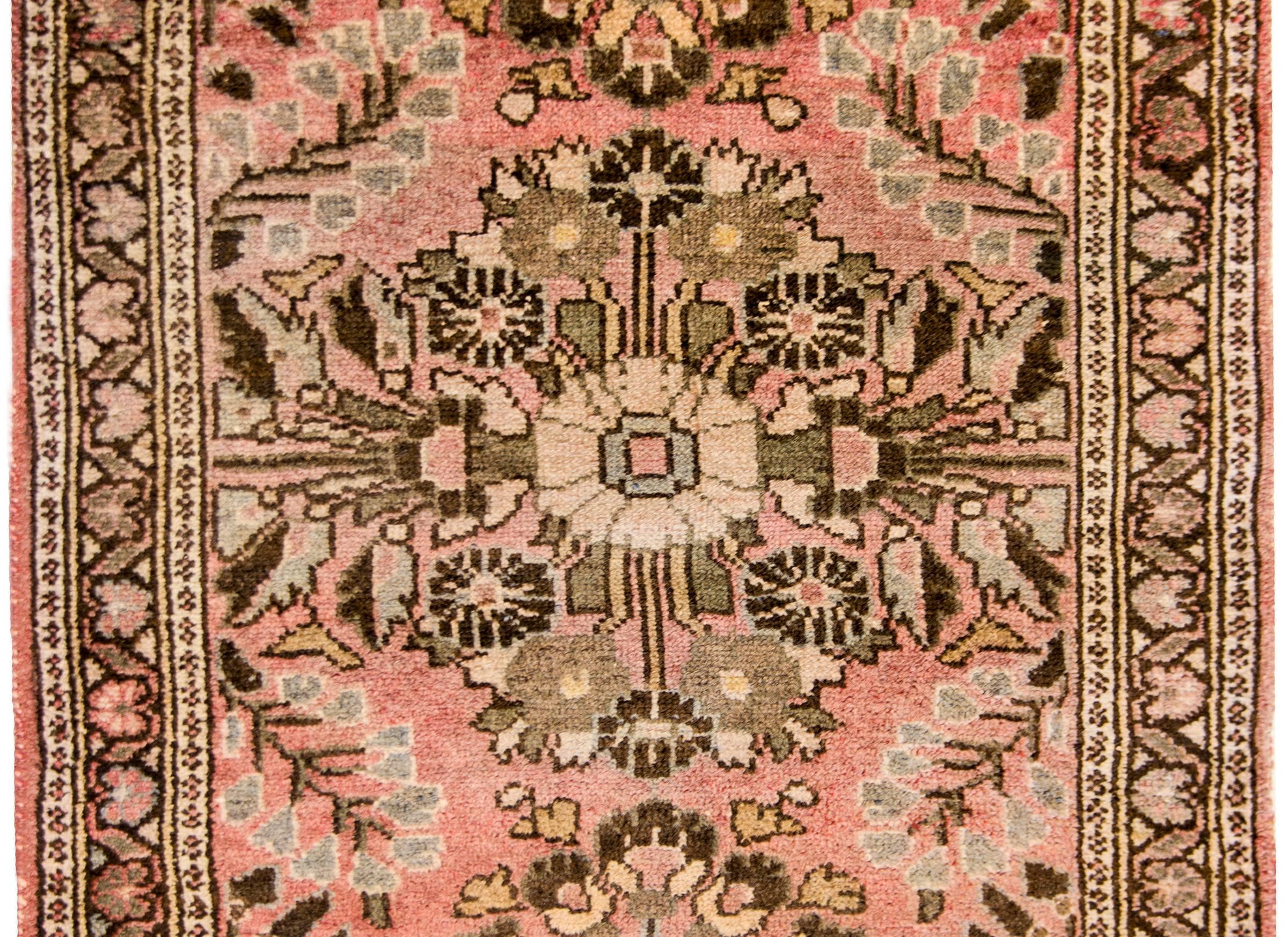 A petite early 20th century Persian Lilihan rug which has been sun faded with sweet all-over mirrored floral pattern woven in dark and light brown, cream, and coral colored wool. The border is complementary with a petite floral and leaf pattern